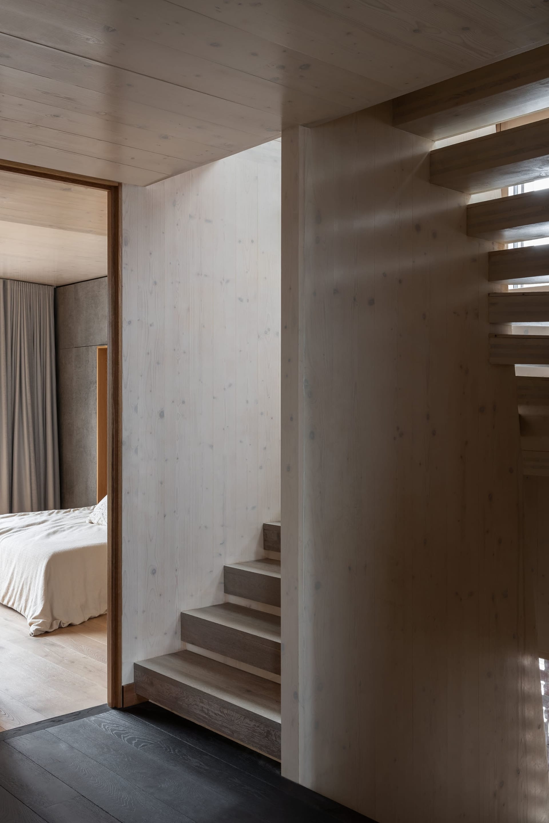 A modern minimalist staircase built from wooden steps and walls.