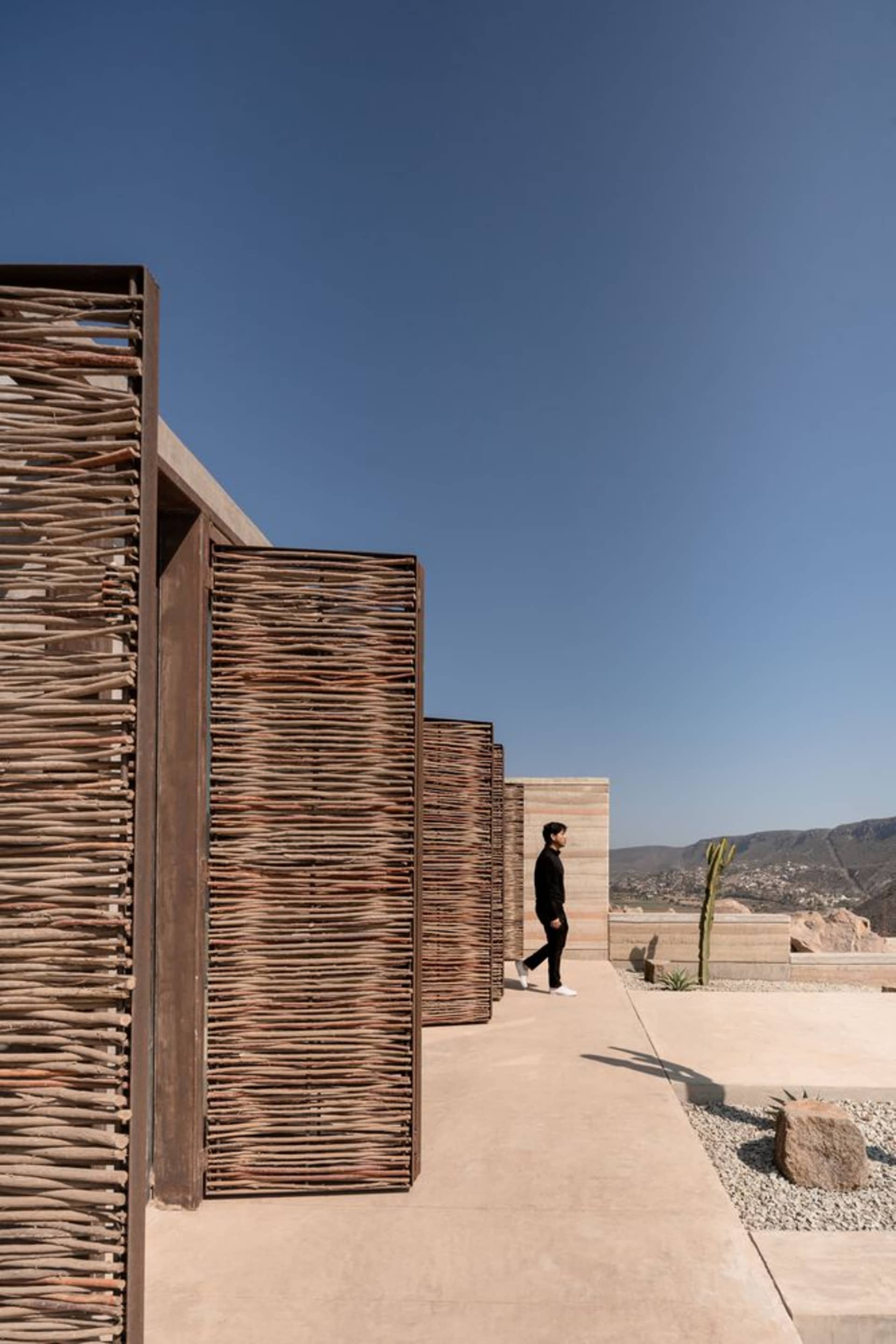 A modern residential exterior featuring wooden walls and concrete pavers.