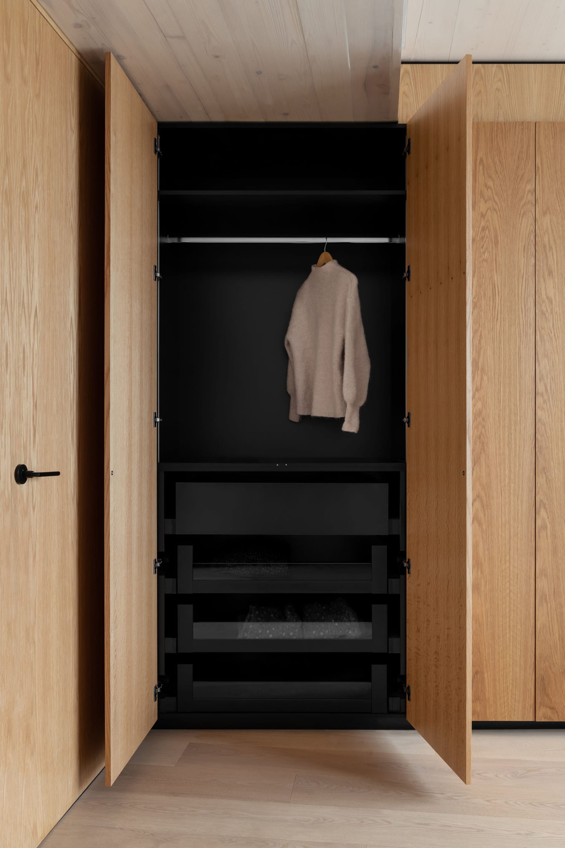A modern wardrobe with wooden doors and black interior, showcasing a minimalist design.