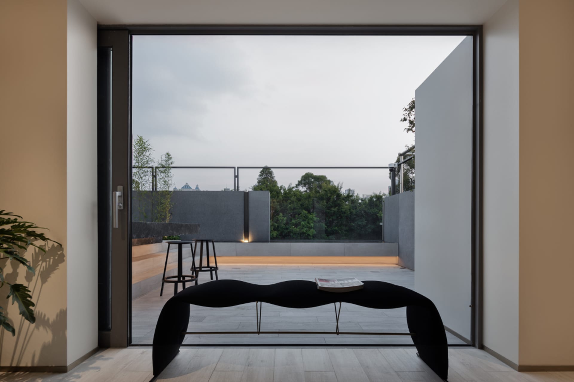 Modern interior space with sleek black bench, glass walls, and concrete flooring.