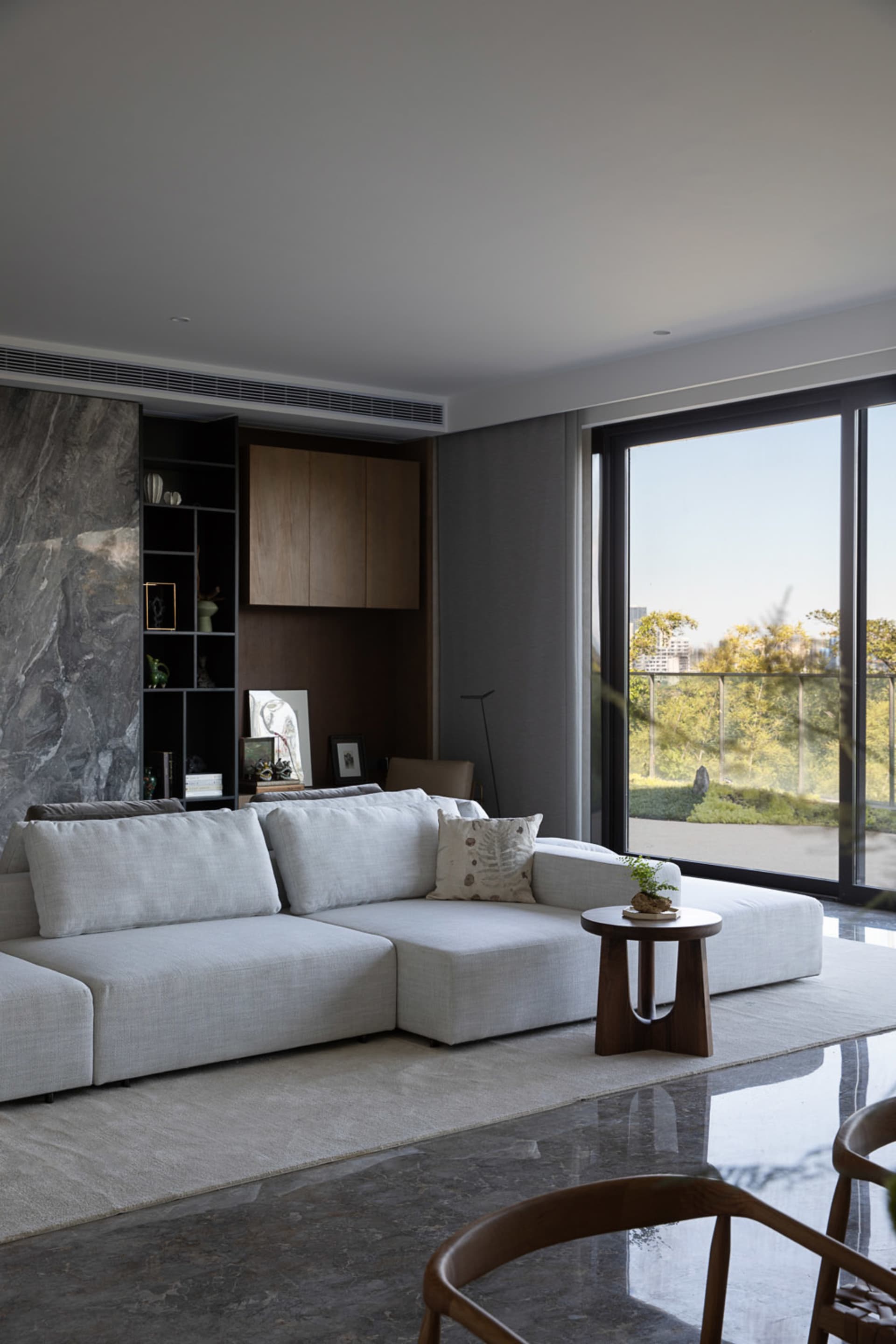 Modern living room with a white sectional sofa, marble fireplace, and large windows.