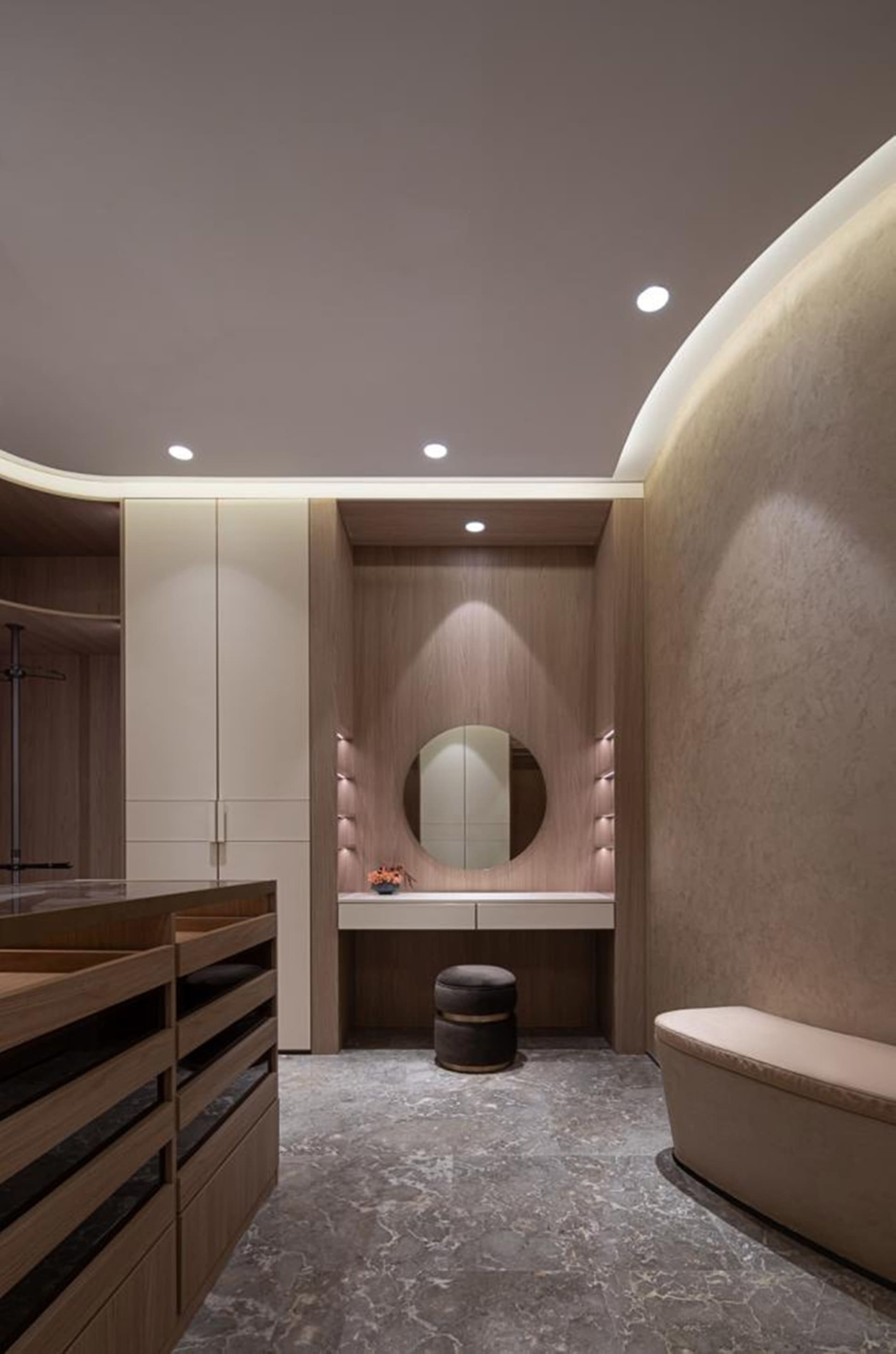 A modern bathroom featuring a marble floor and wood accents, with a vanity area illuminated by soft lighting.