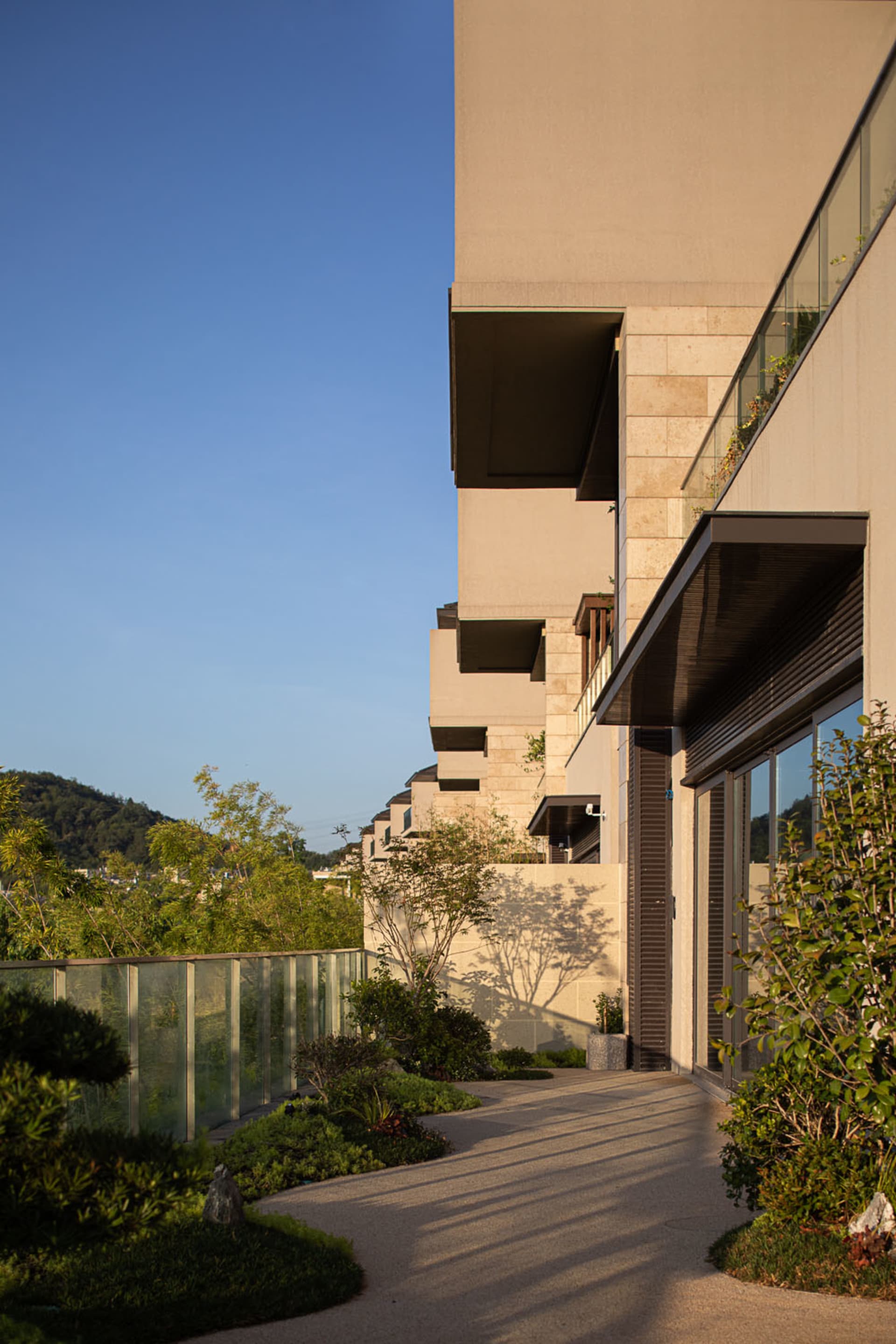 A modern residential building with concrete exterior walls and extensive greenery.