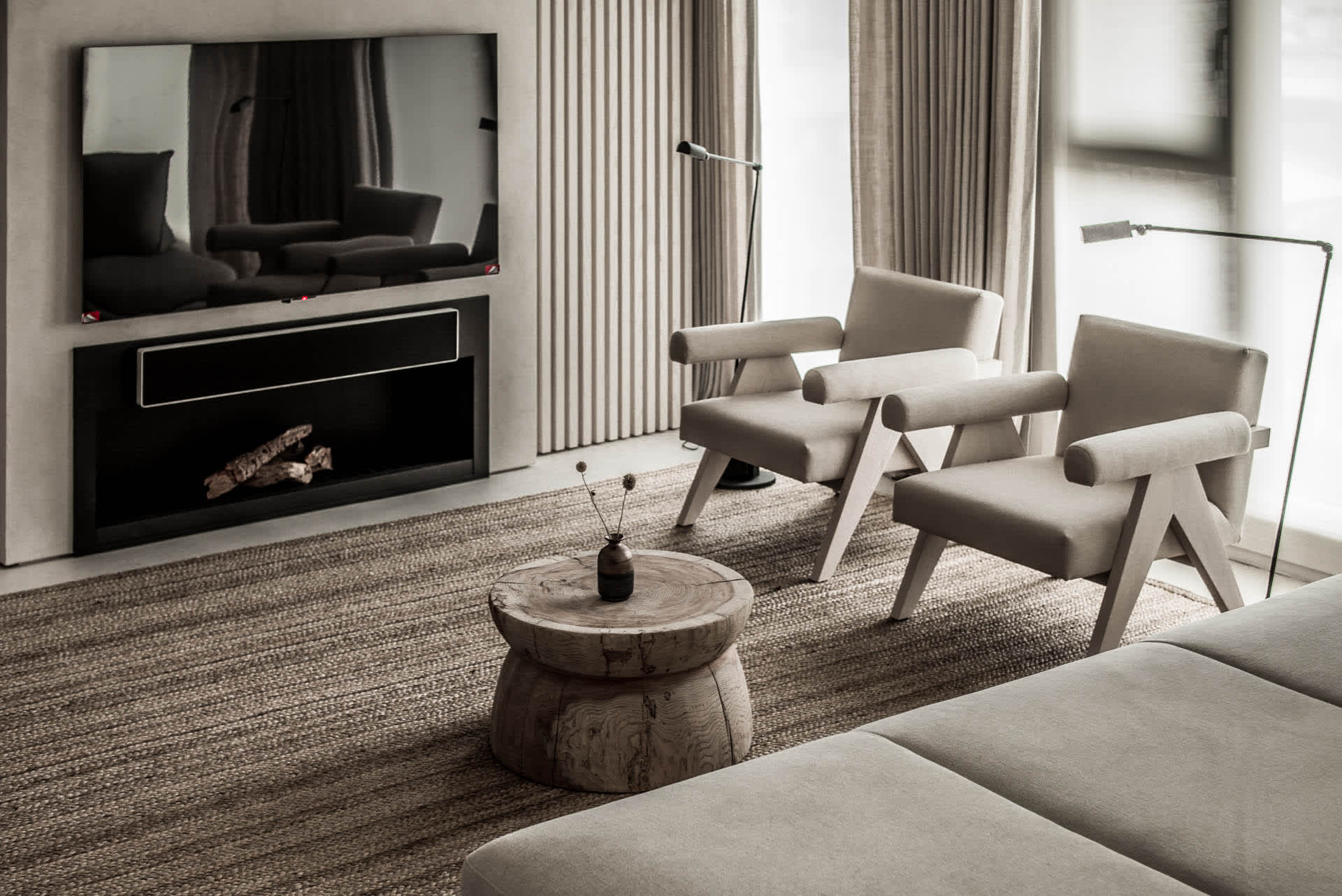 A modern minimalist living room with cushioned furniture, a wooden table, and a flat-screen TV mounted on the wall.