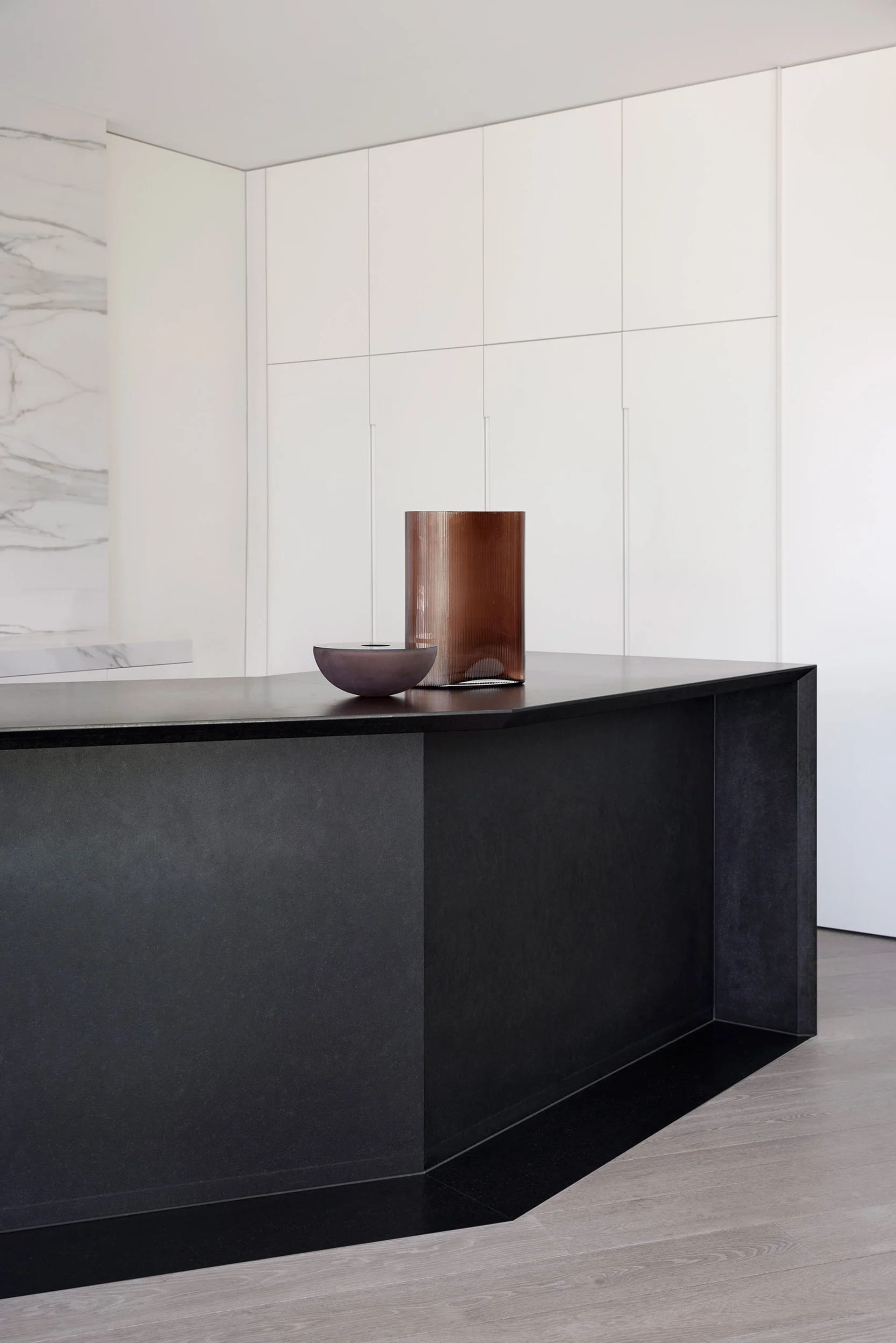 A modern kitchen with sleek, dark concrete countertops and minimalist white cabinets.