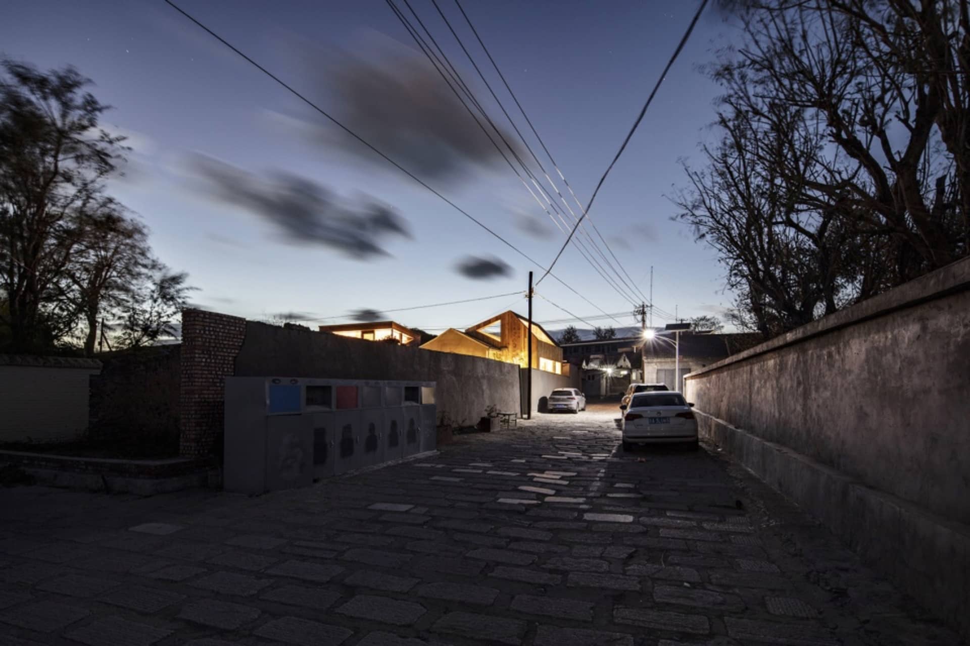 黃昏時分的鵝卵石街道，建築物與汽車在燈光照耀下。