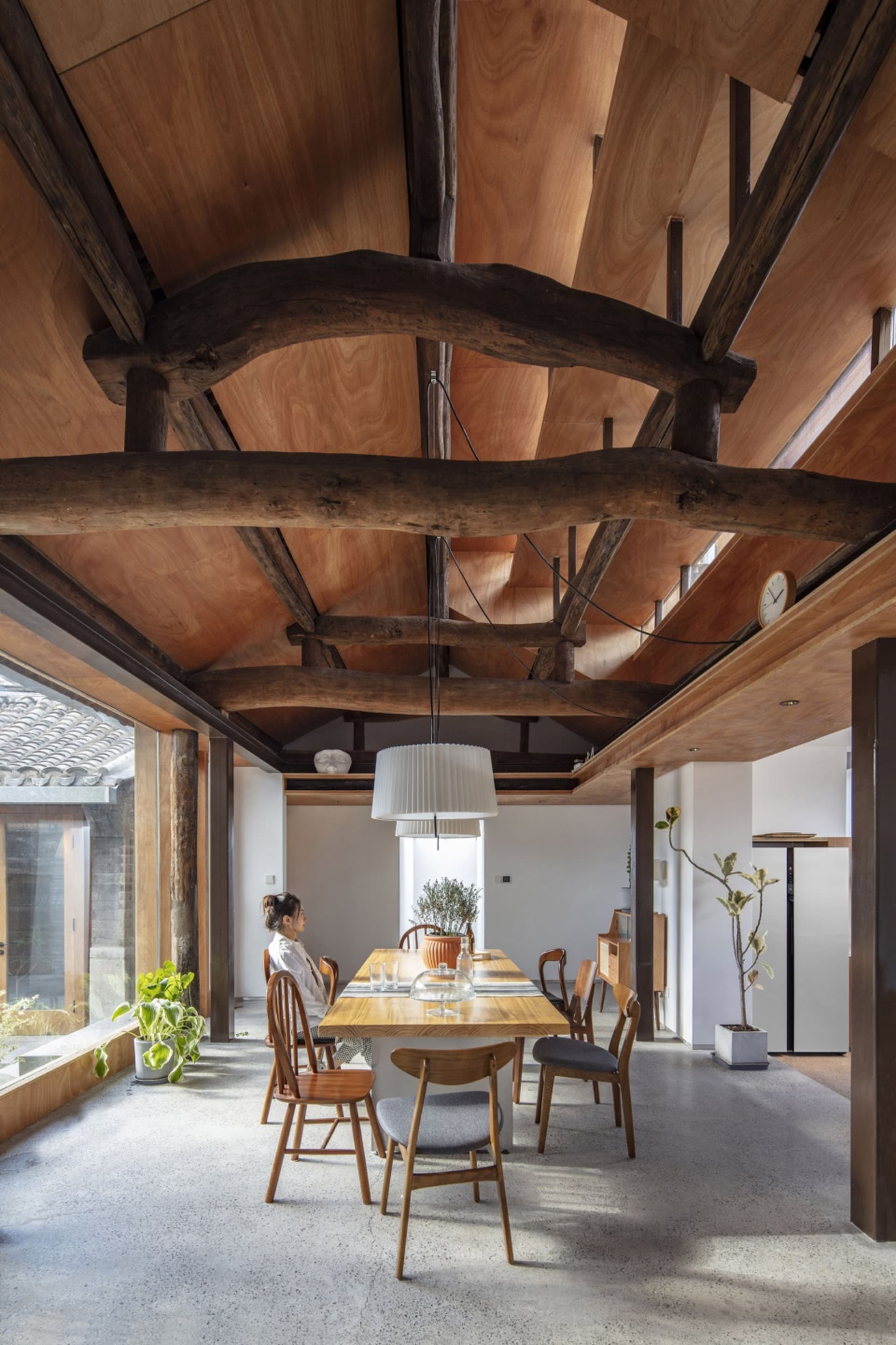 A modern, industrial dining room with exposed wooden beams on the ceiling.