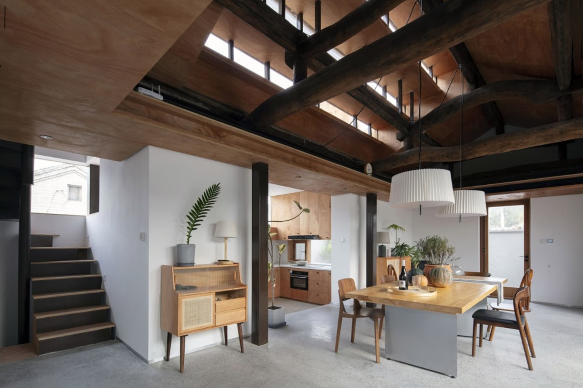 A modern residential kitchen with an industrial design aesthetic featuring concrete walls, glass windows, and wood accents.