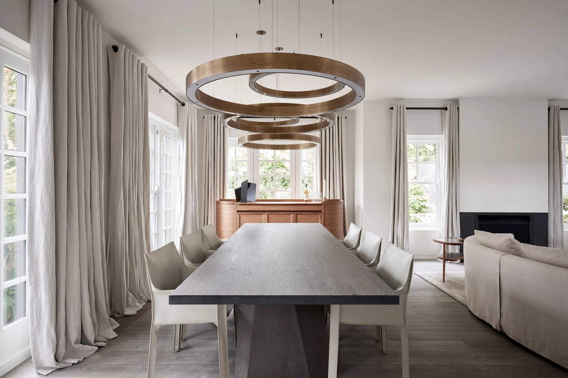 Modern dining room featuring natural wood dining table and chairs, with large windows, pendant lighting, and clean lines.