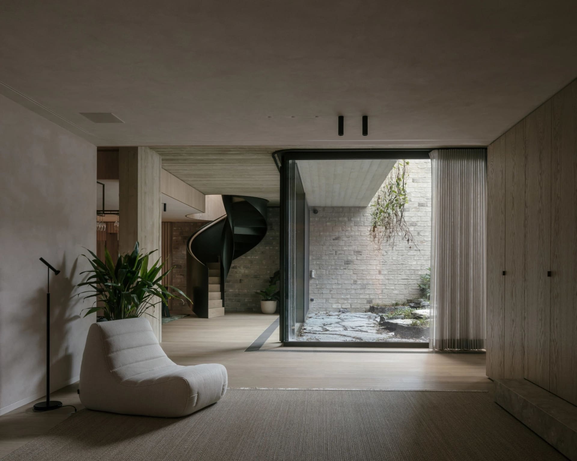 A modern living room featuring wooden flooring, minimalist furniture, and contemporary decor.