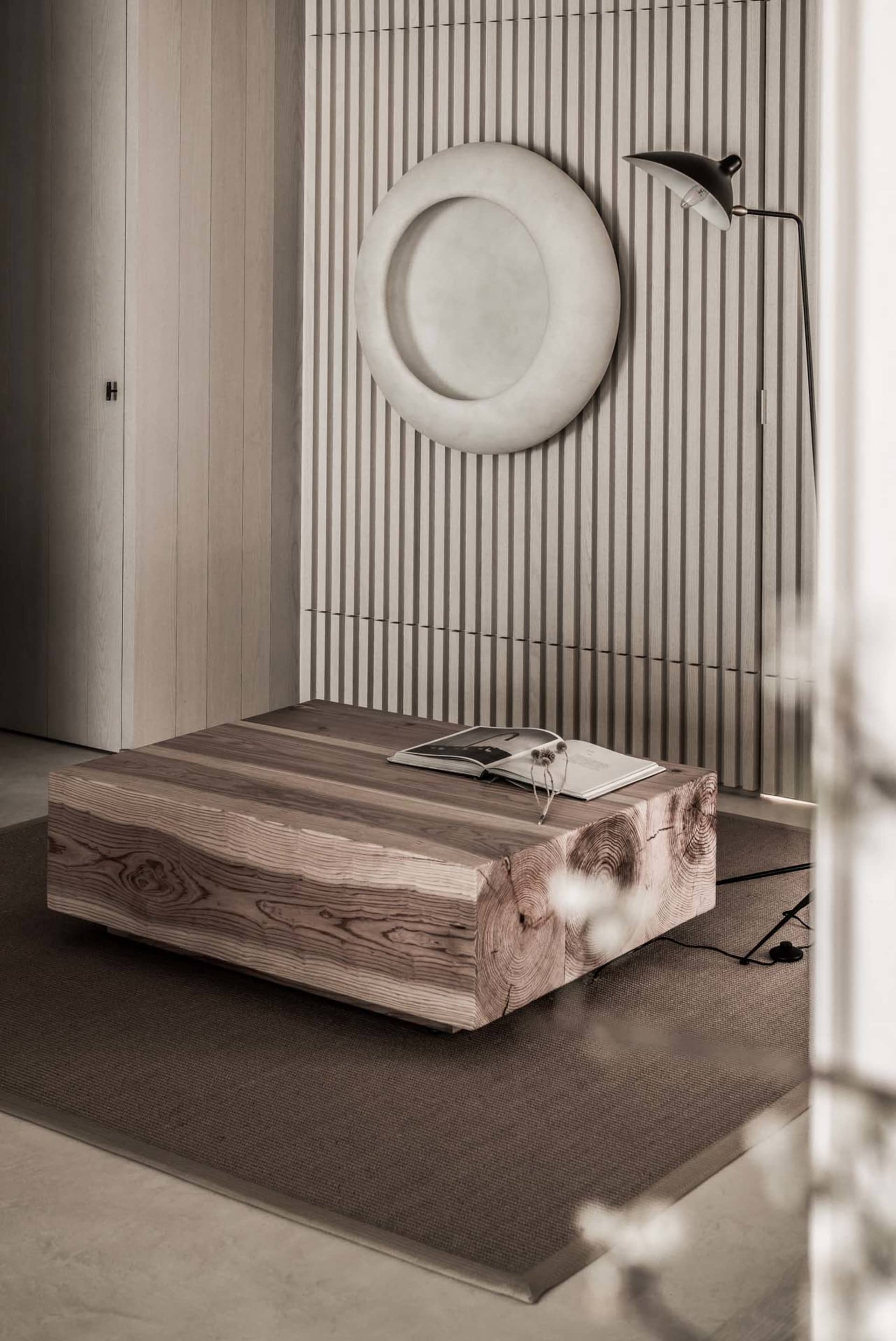 A modern, minimalist living room featuring a wooden coffee table with natural wood grains and a geometric design, complemente