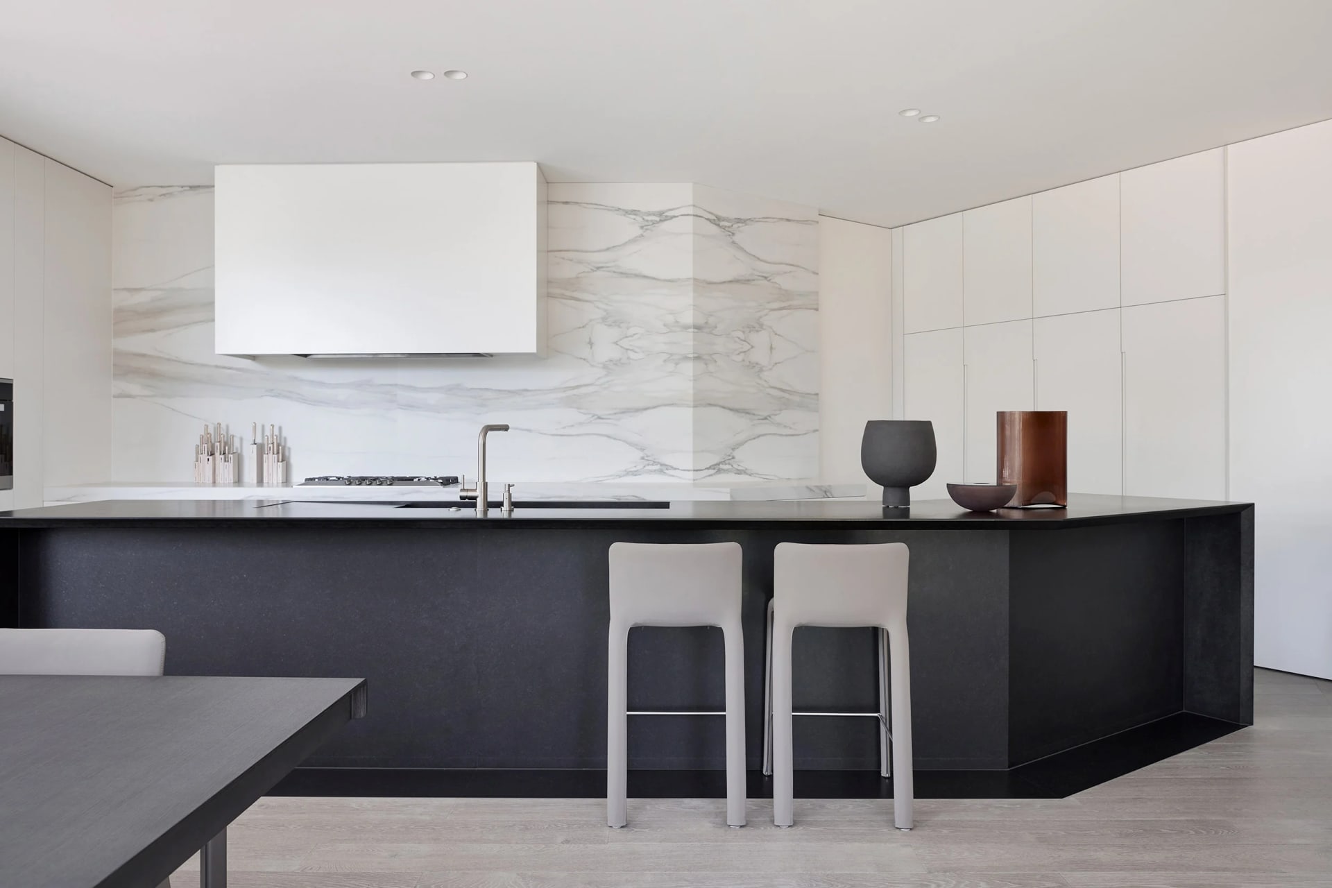 A modern residential kitchen featuring marble countertops and backsplash.