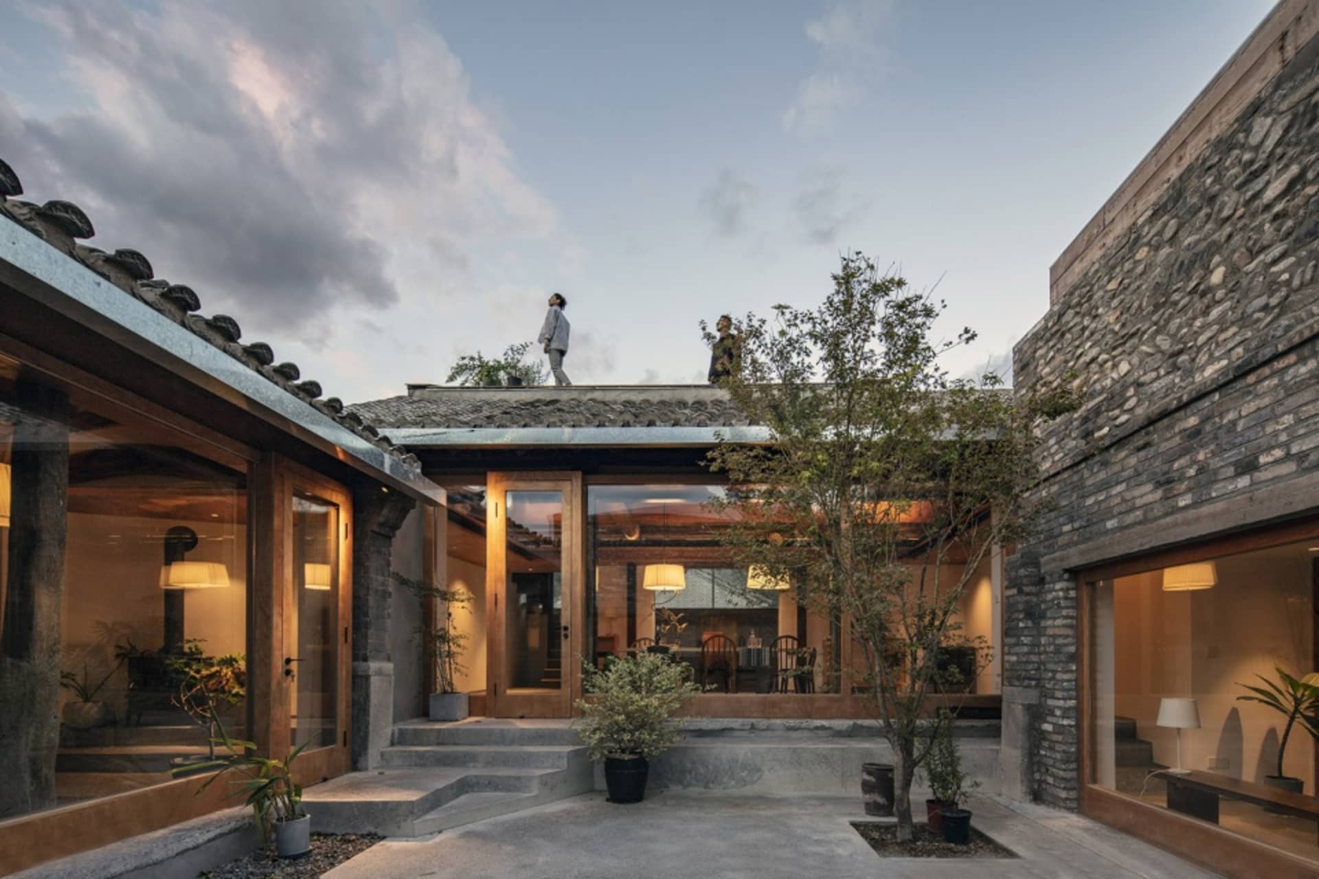 A cozy courtyard with wooden doors, concrete steps, and stone walls and roofs in a residential Chinese-style home.