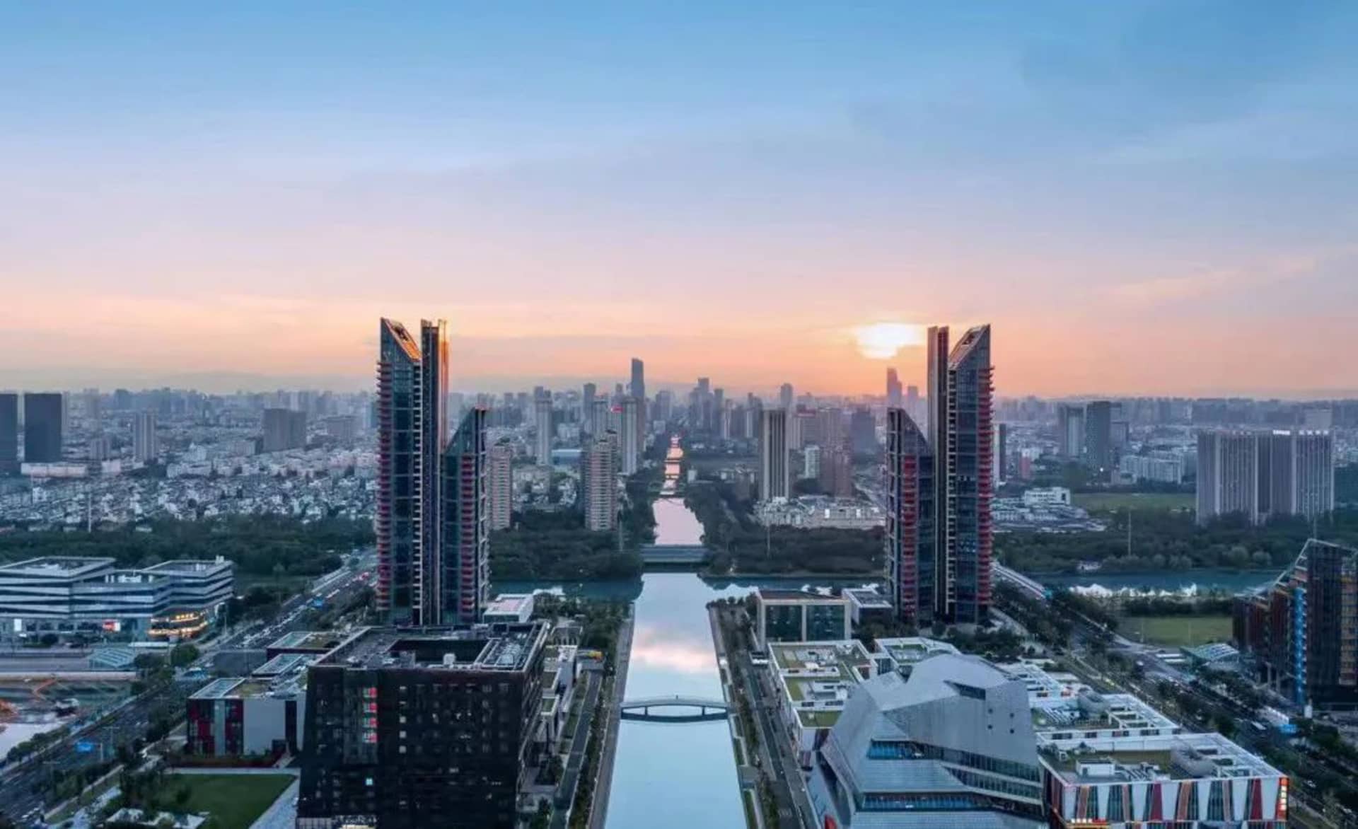 現代都市景觀，玻璃、混凝土與鋼材建築在夕陽中呈現。
