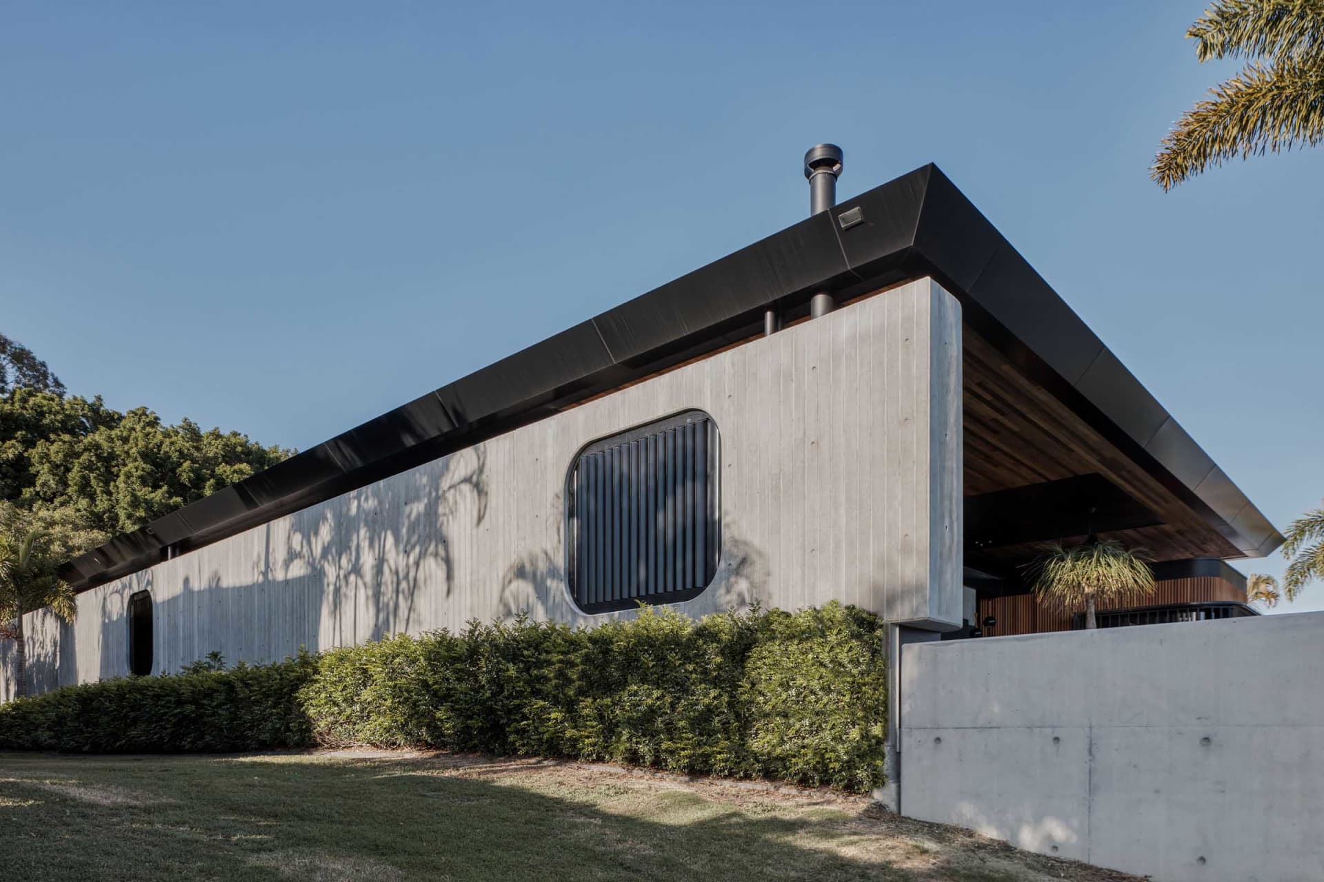 A modern house with a sleek, angular design featuring concrete walls and an open-air patio.