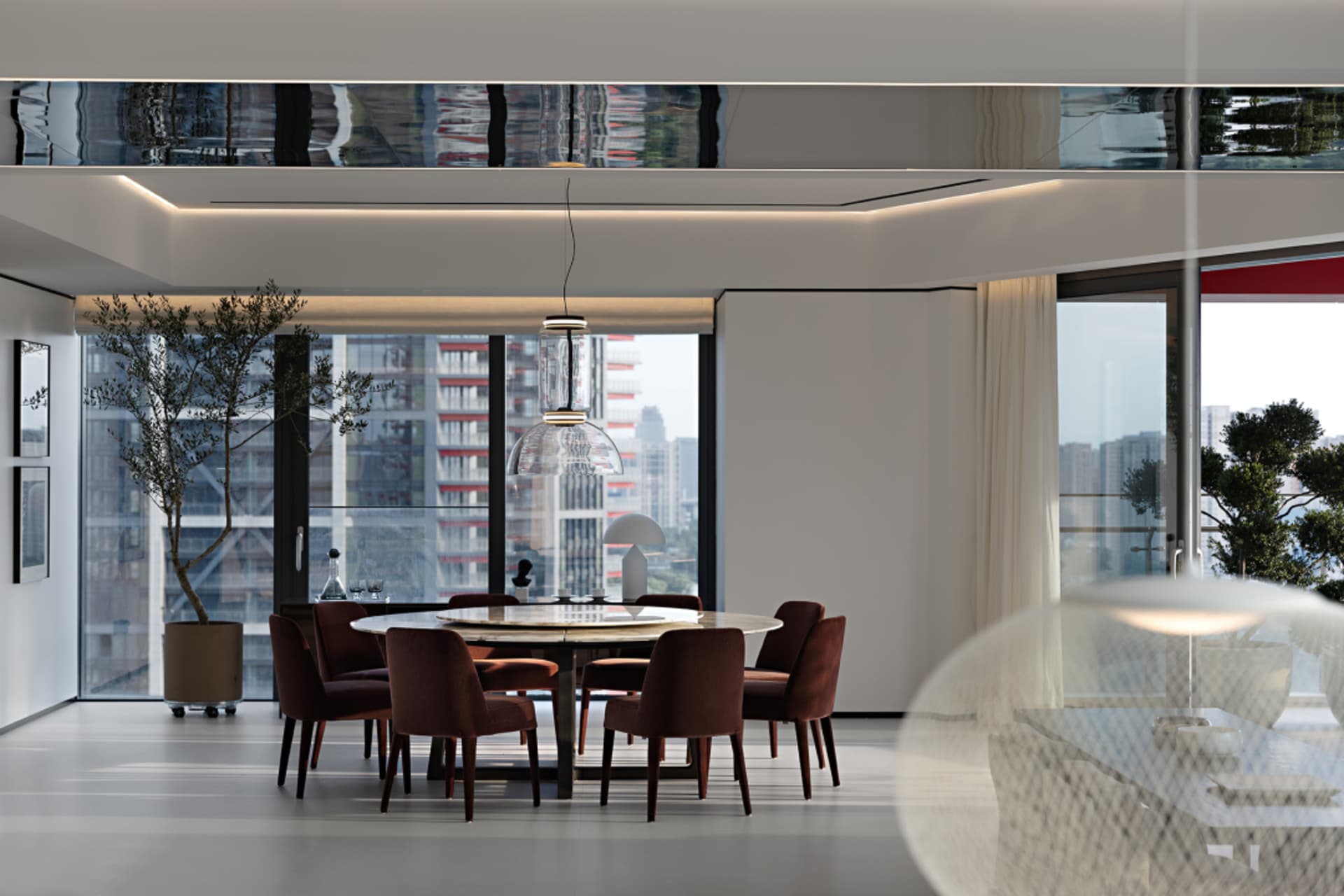 A modern dining room featuring a round table and chairs surrounded by a glass window.