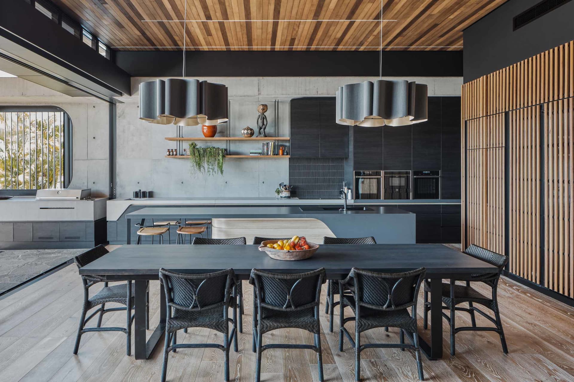 A modern and industrial residential kitchen featuring black matte finishes and concrete materials, showcasing clean lines and