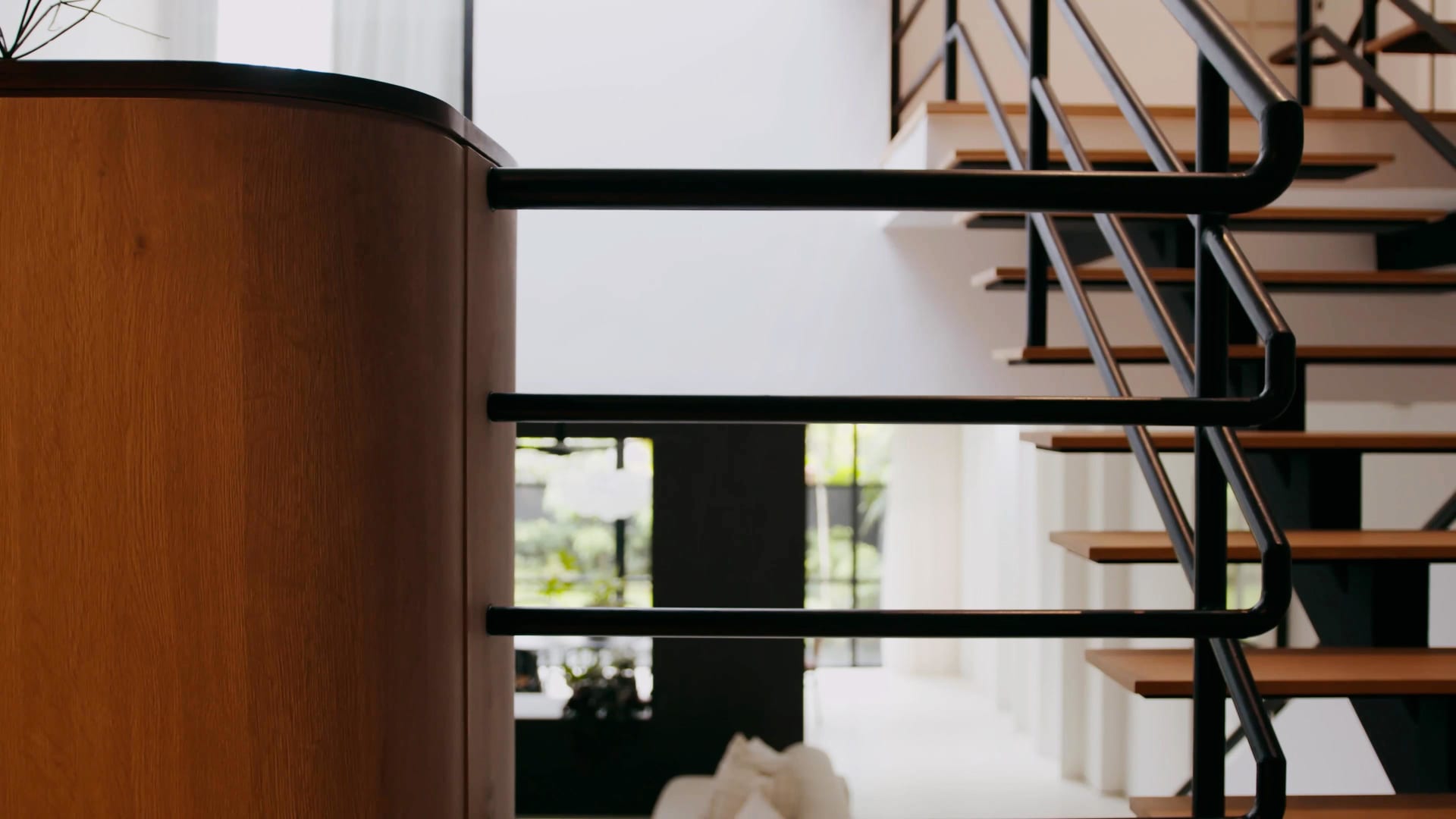 Modern interior design featuring a metal and wood staircase with black handrails.