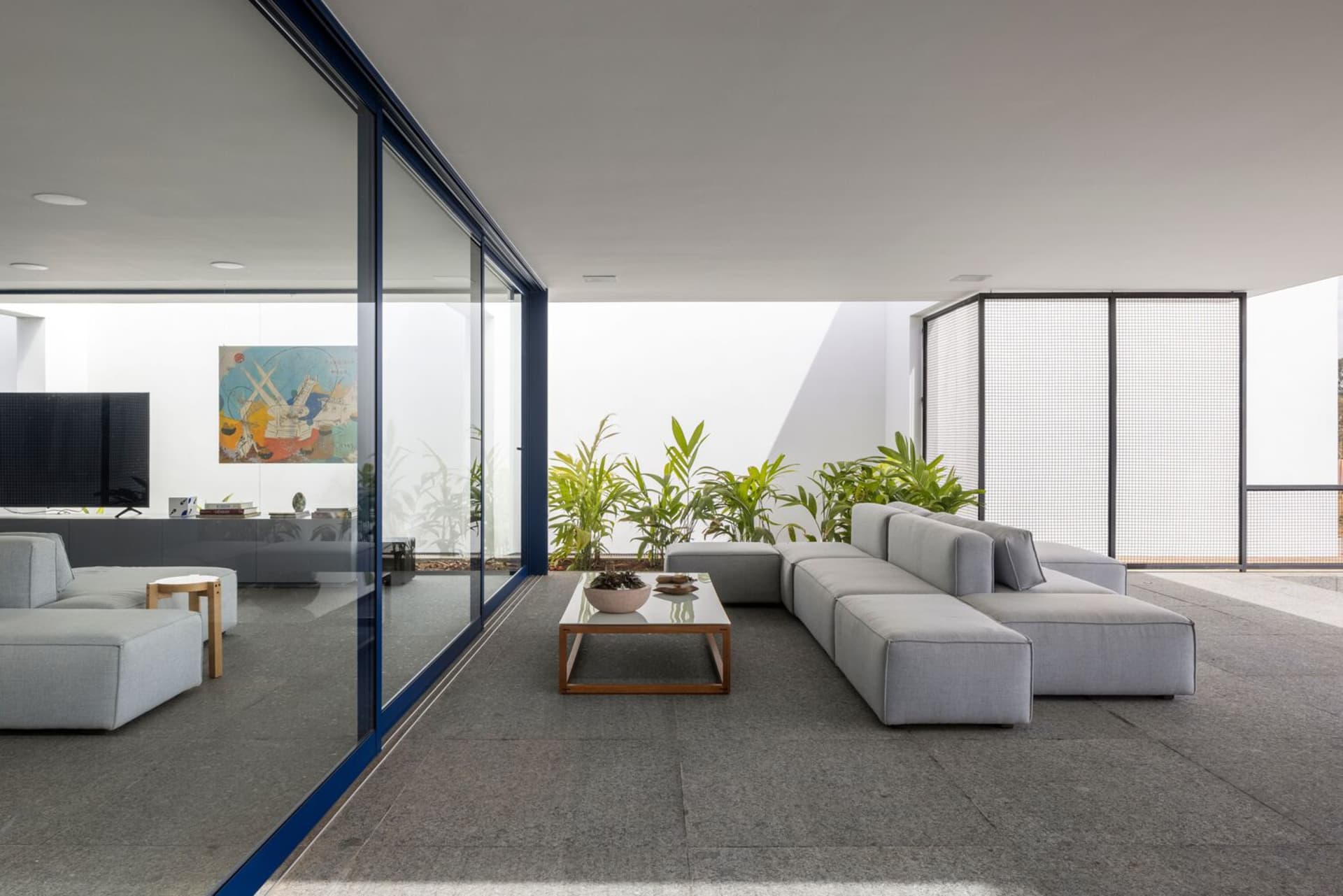 Modern living room with concrete floor and large windows.