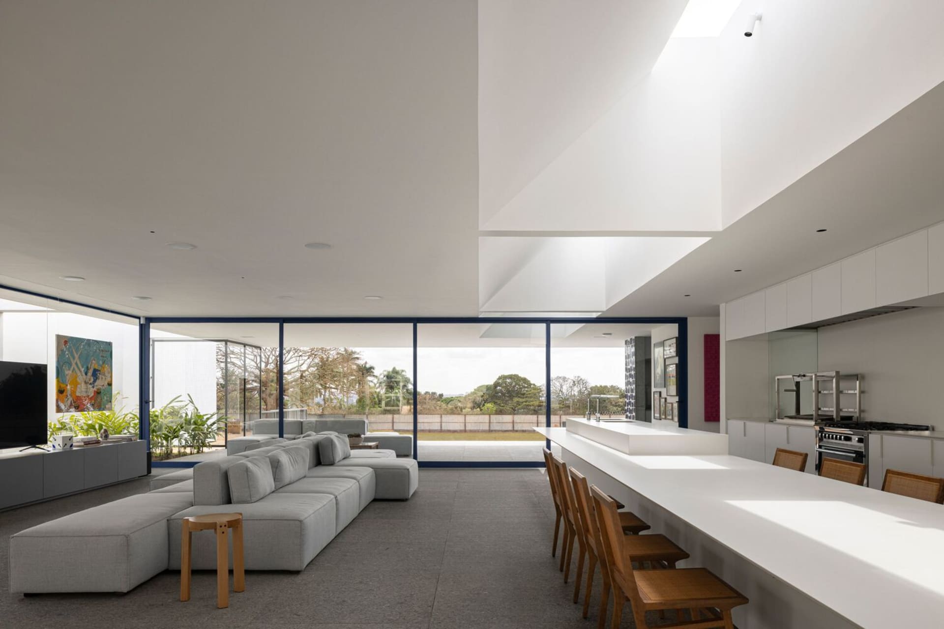 A modern living room with large glass windows allowing natural light in, an open-plan layout, and a comfortable seating area.