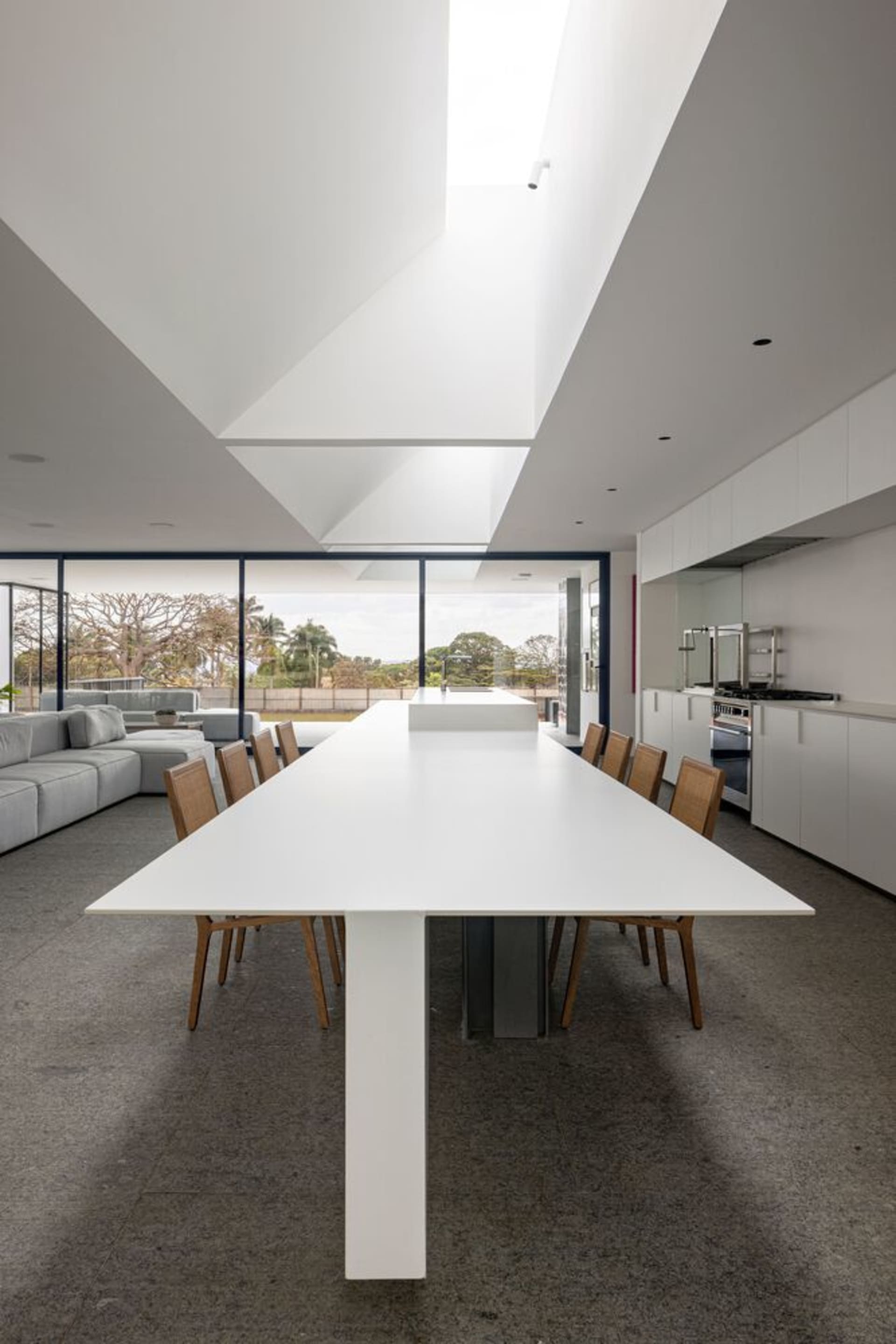 Modern white concrete dining room with large windows and natural light.