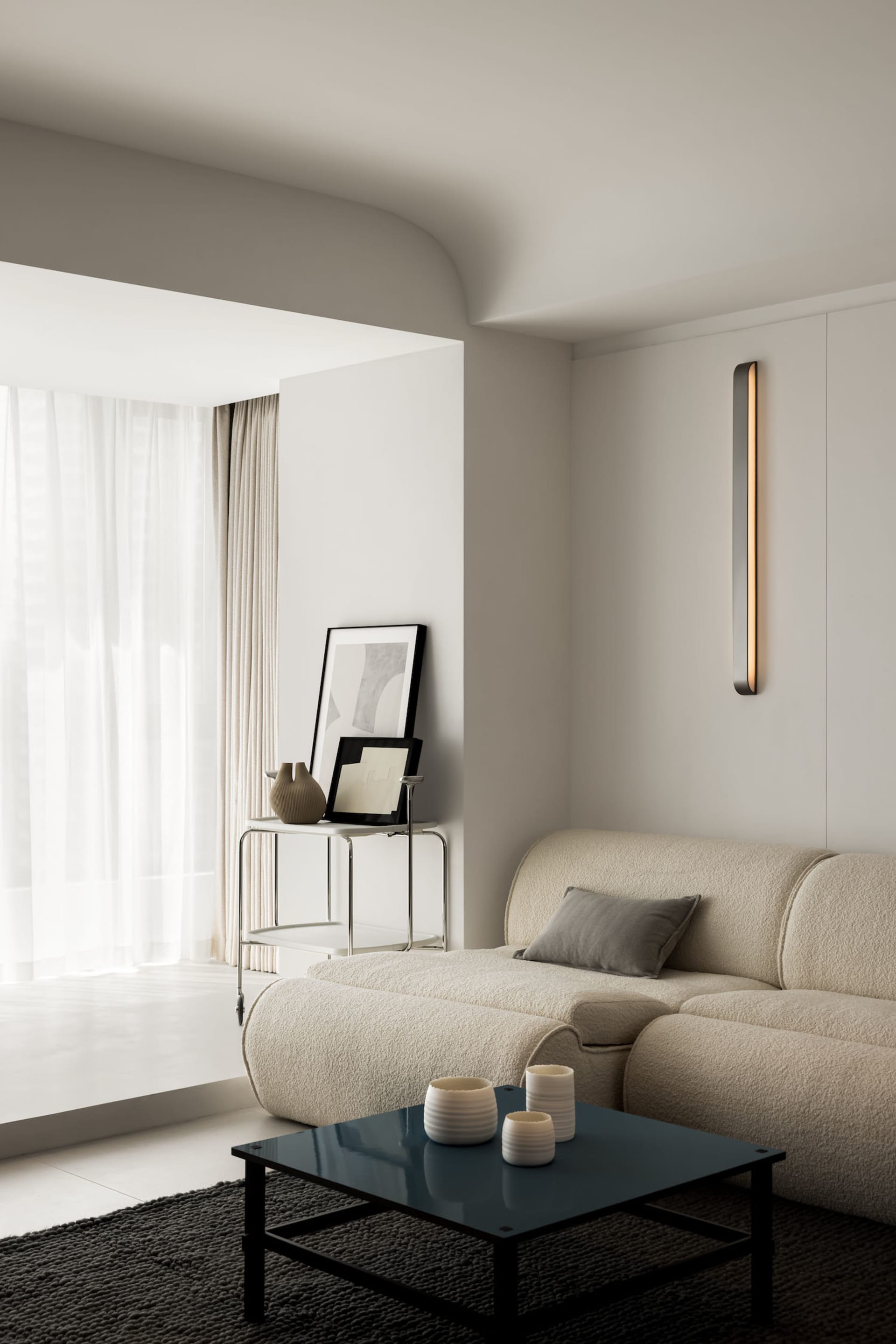 Modern minimalist living room with textured fabric sofa, metal side table, glass vase, and wooden coffee table.