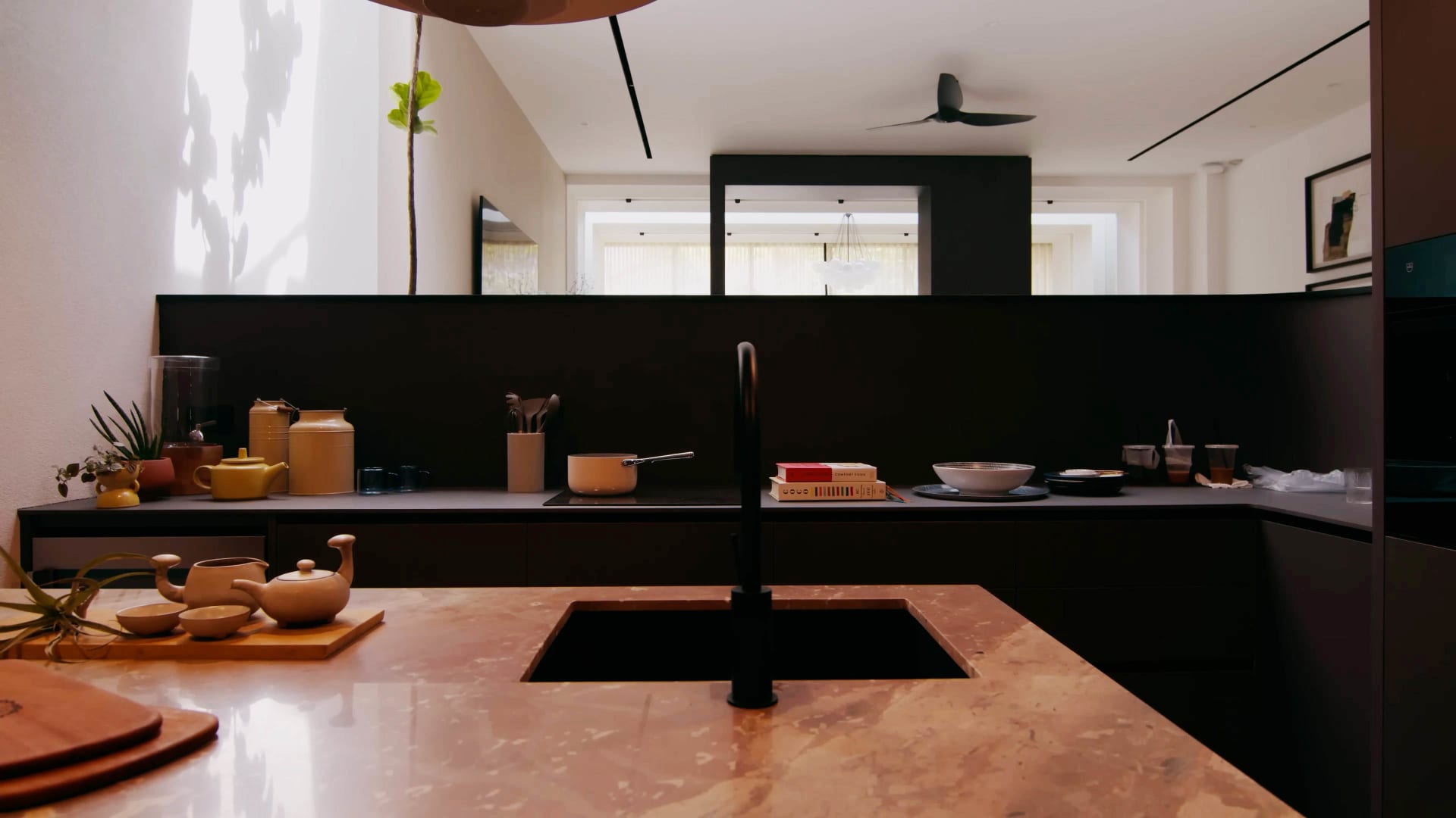Modern kitchen with marble countertops and yellow teapots.