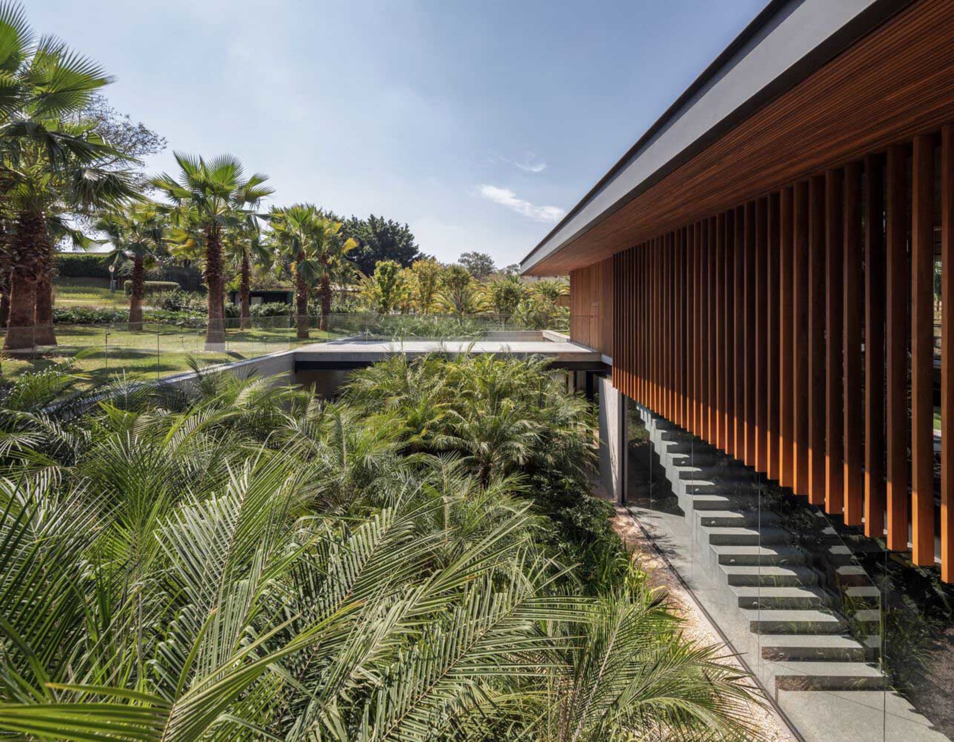 Modern residential exterior featuring a wooden exterior with large glass windows and a concrete foundation.