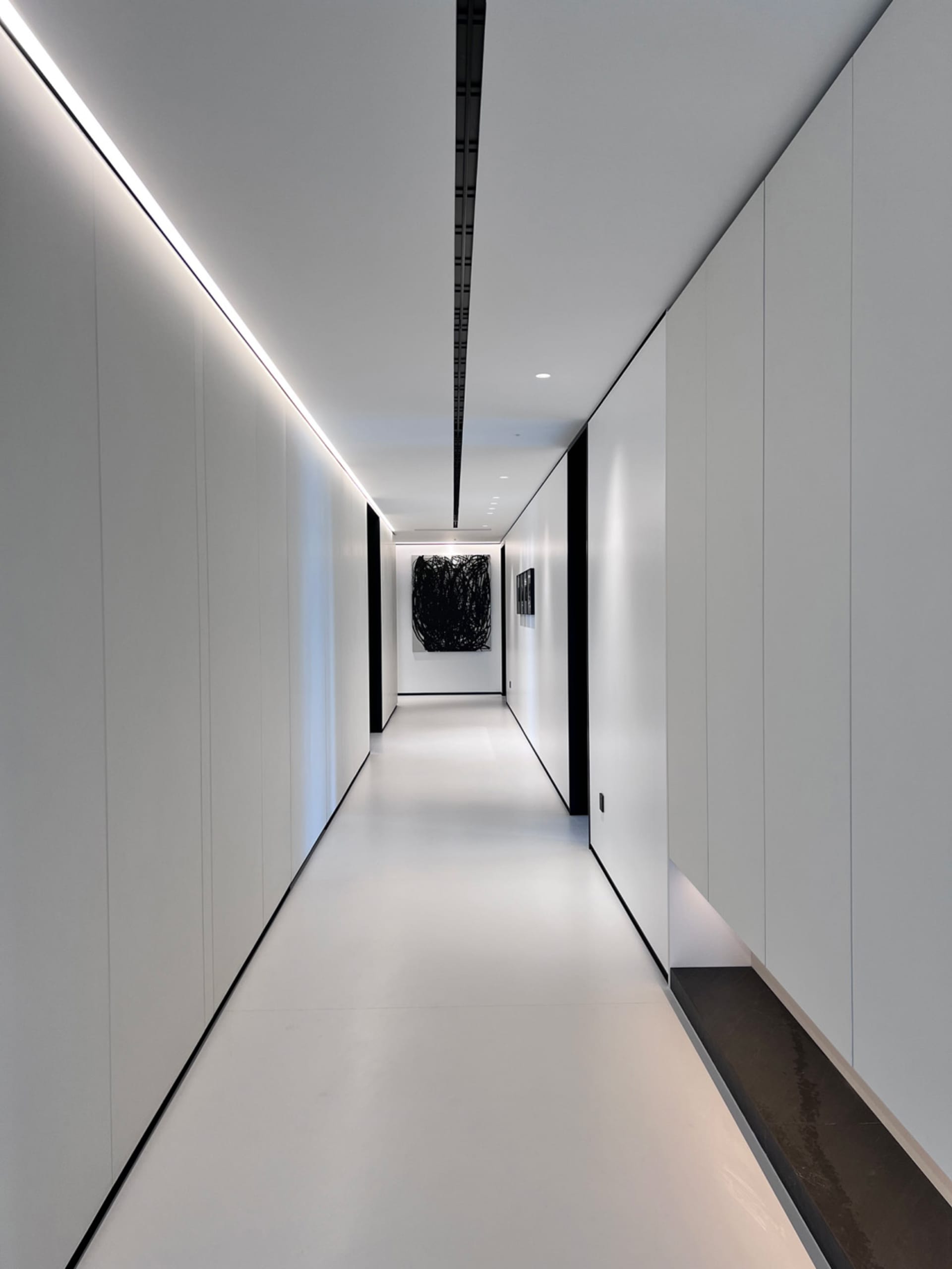 A minimalist white corridor with panels on the walls.