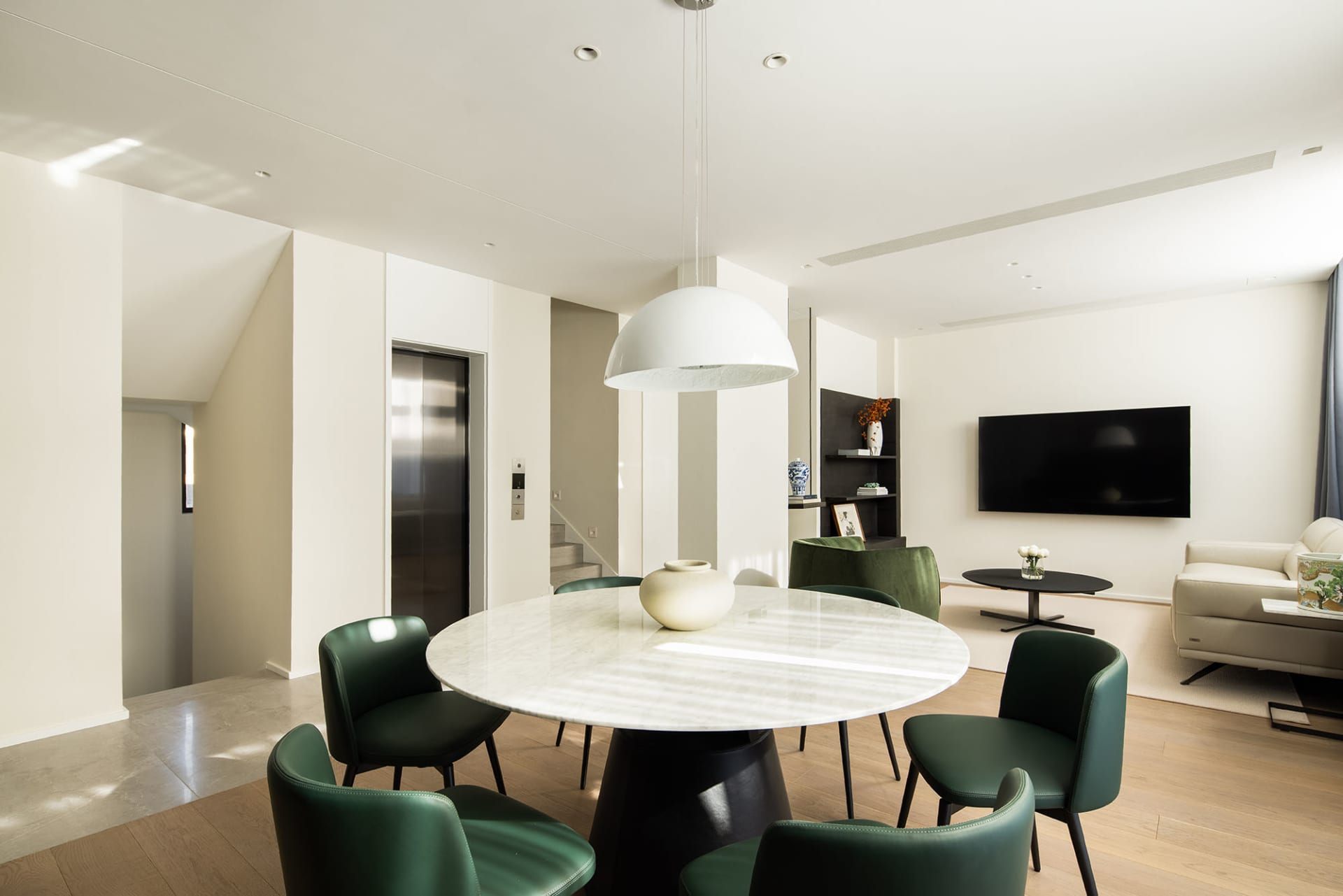 Contemporary living room with marble table and green chairs.