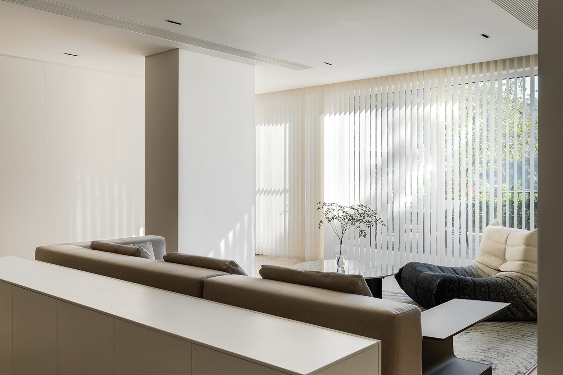 A spacious, minimalist living room featuring neutral materials and a serene atmosphere.
