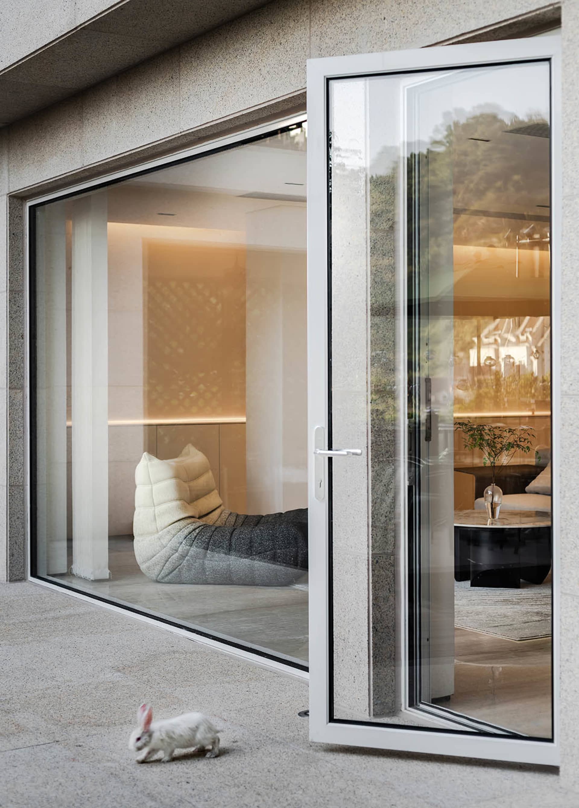 A modern minimalist living room with a glass door and a cozy seating area.