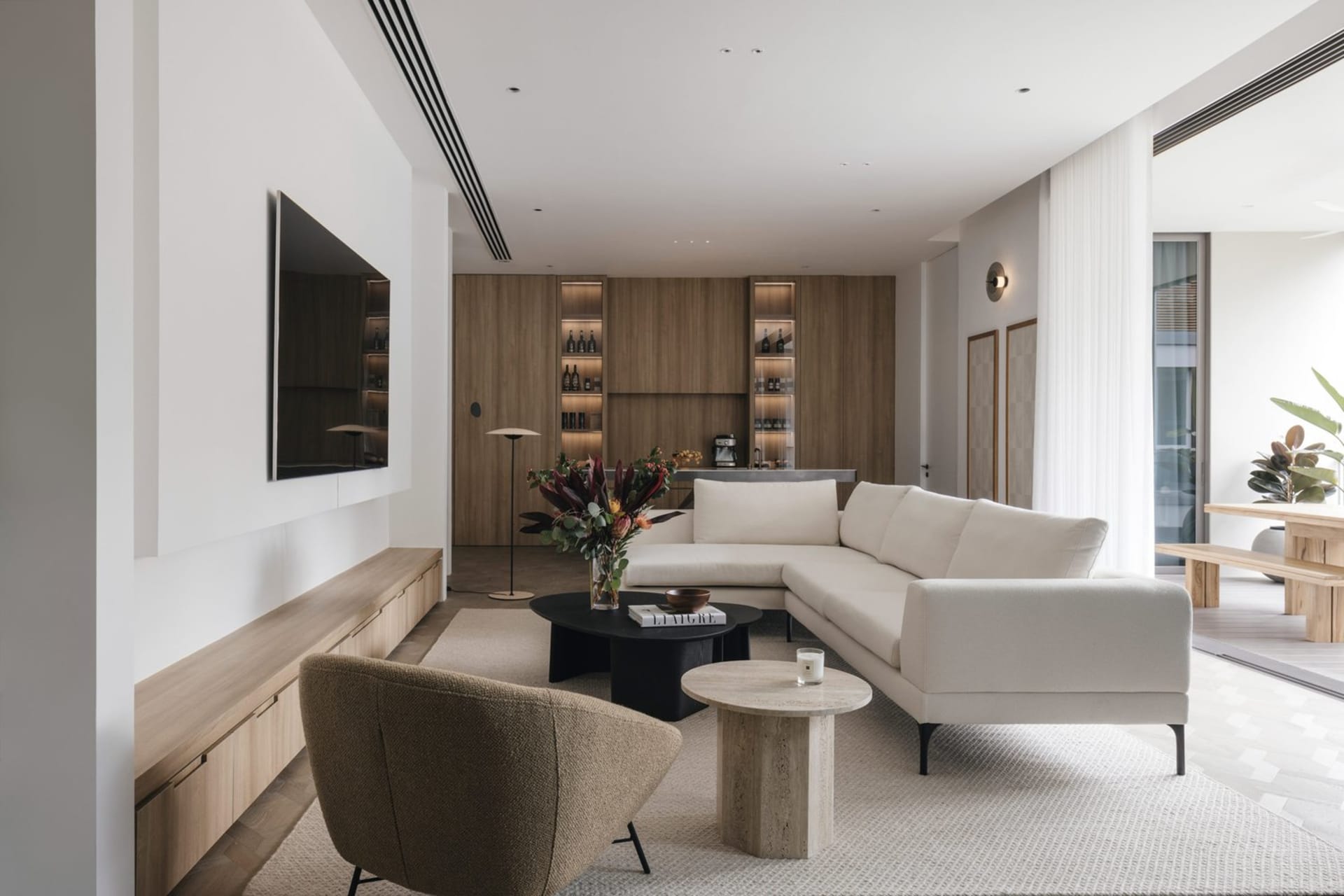 Modern living room featuring a beige sectional sofa, wooden coffee table, and a stone coffee table.