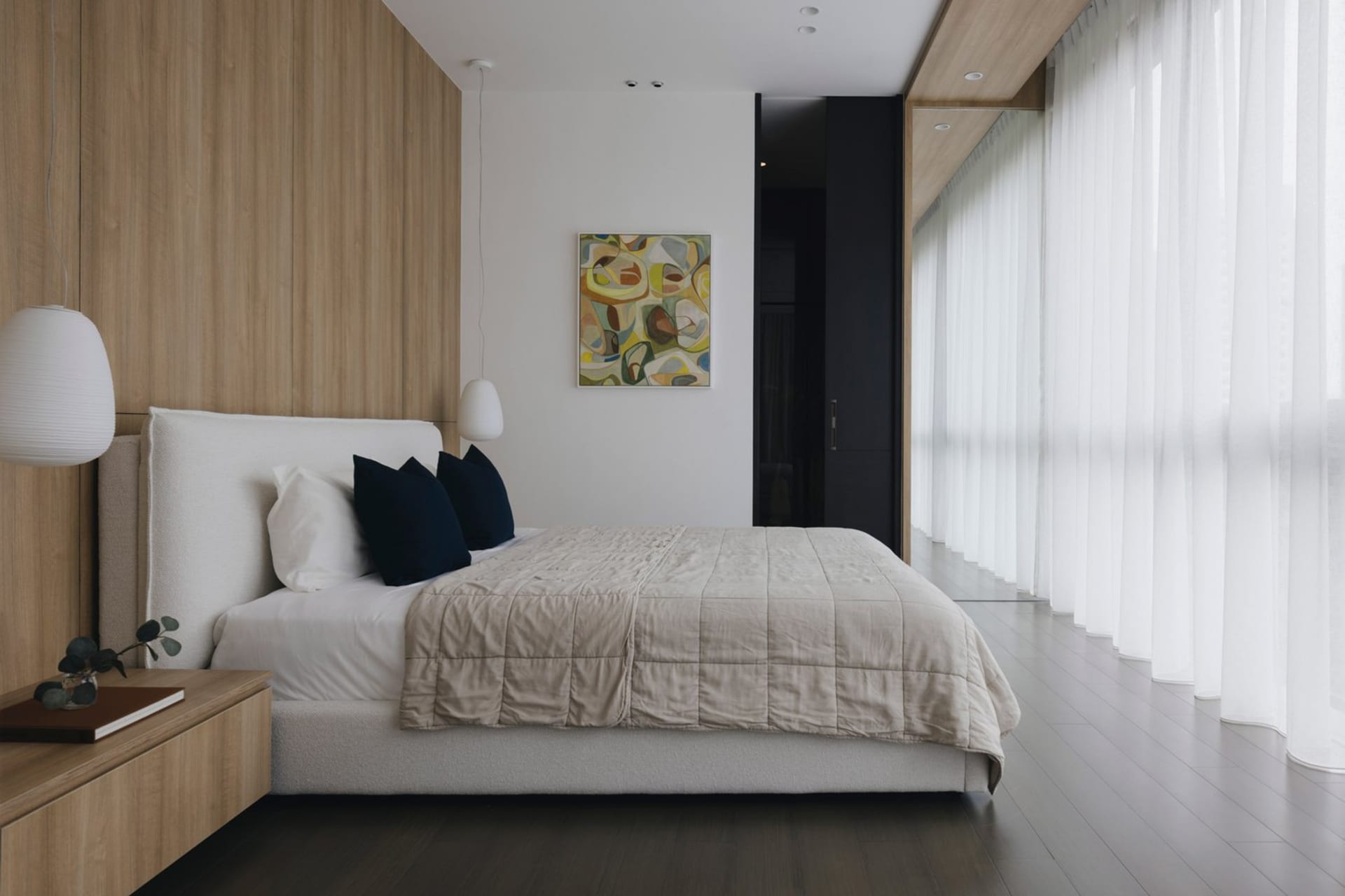 A modern bedroom with a wooden headboard, white bedding, and abstract art on the wall.