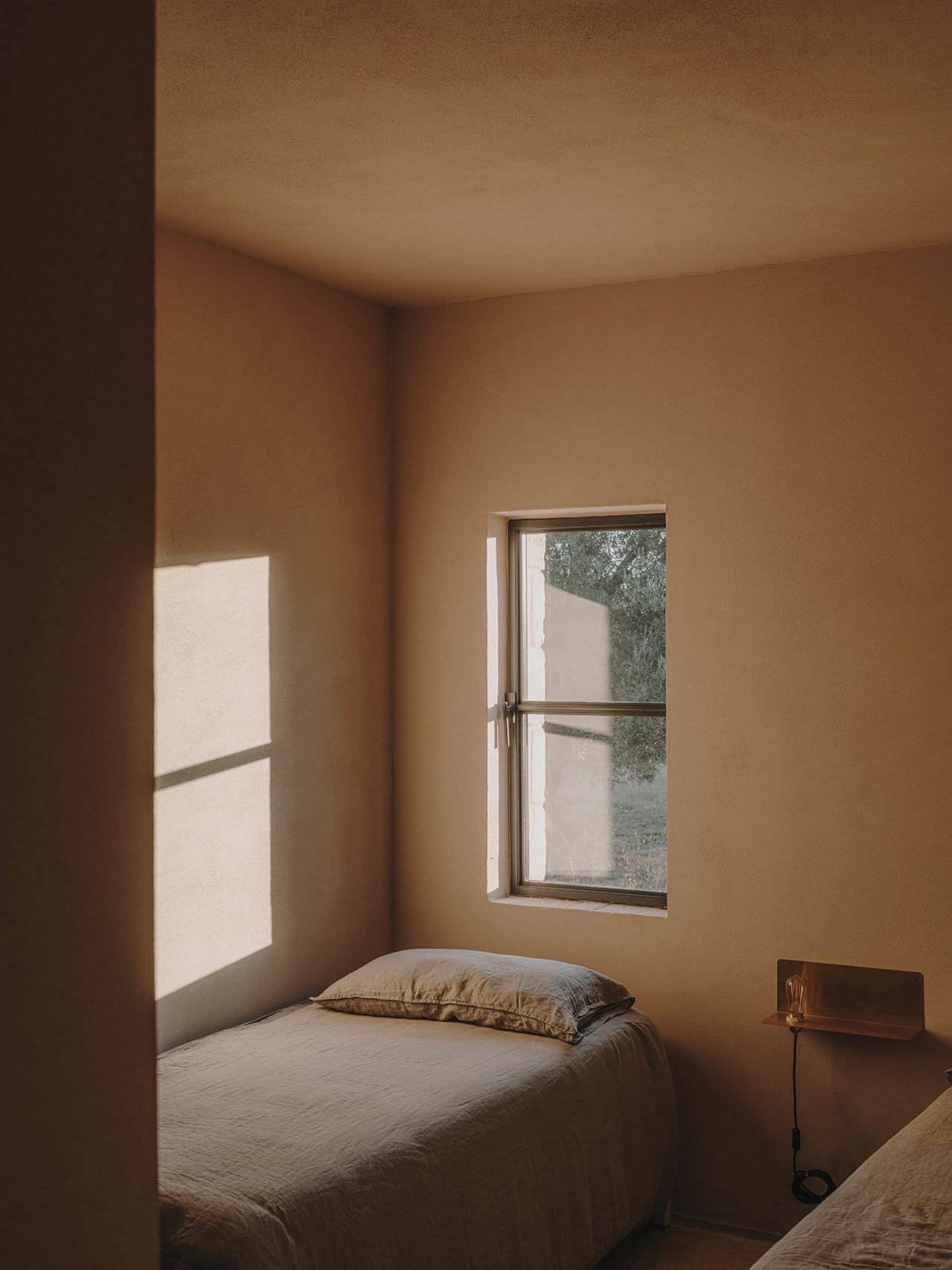 A minimalist bedroom with neutral-colored walls and a single window.