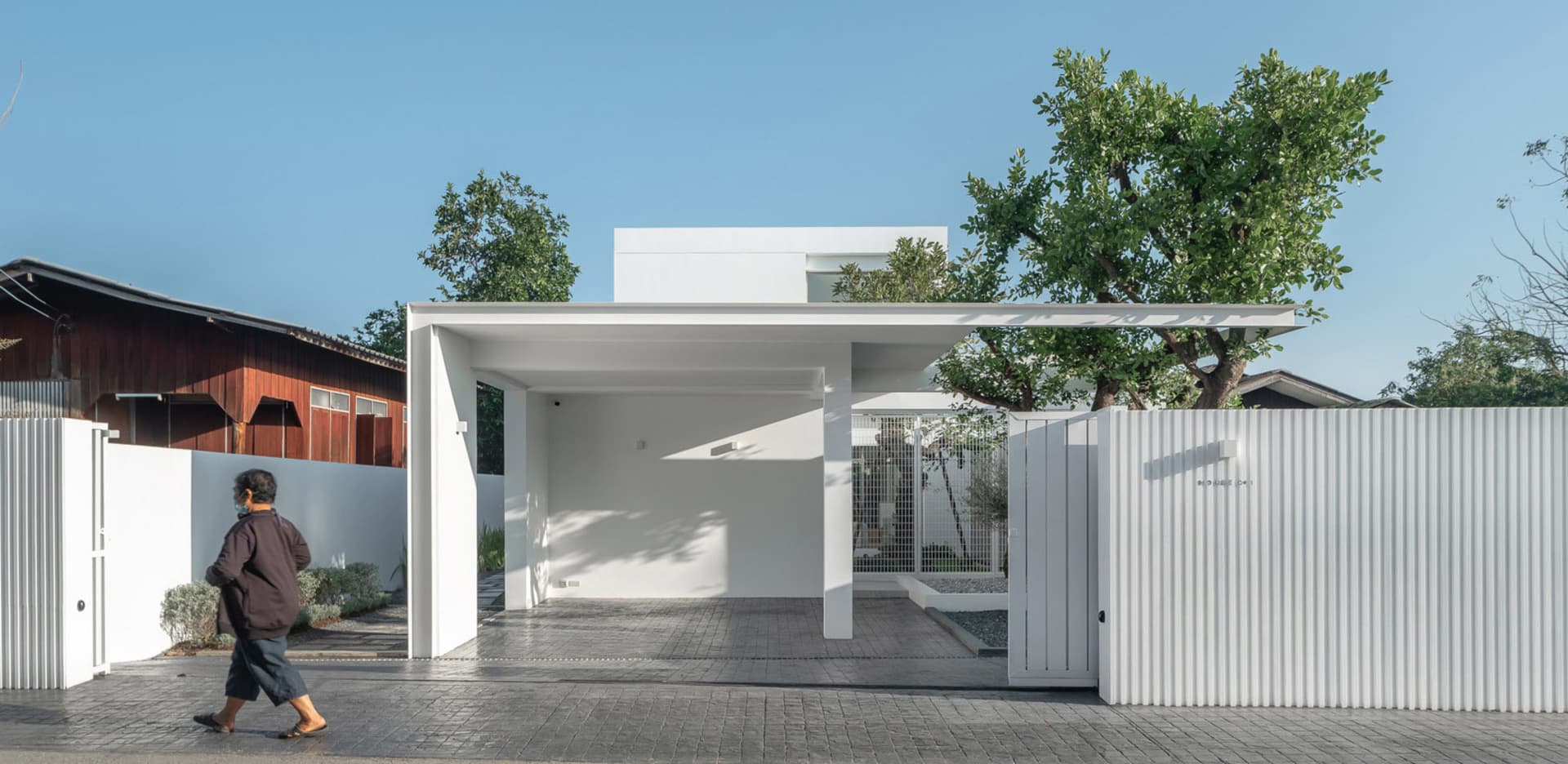 A minimalist house with a white exterior, featuring concrete and metal materials.