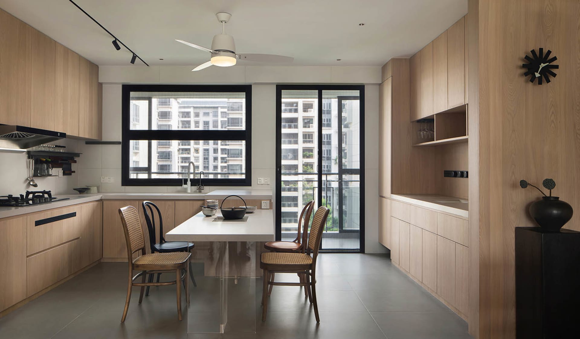 Modern residential kitchen featuring tall wood cabinets, a white dining table, and a clear glass dining table base.