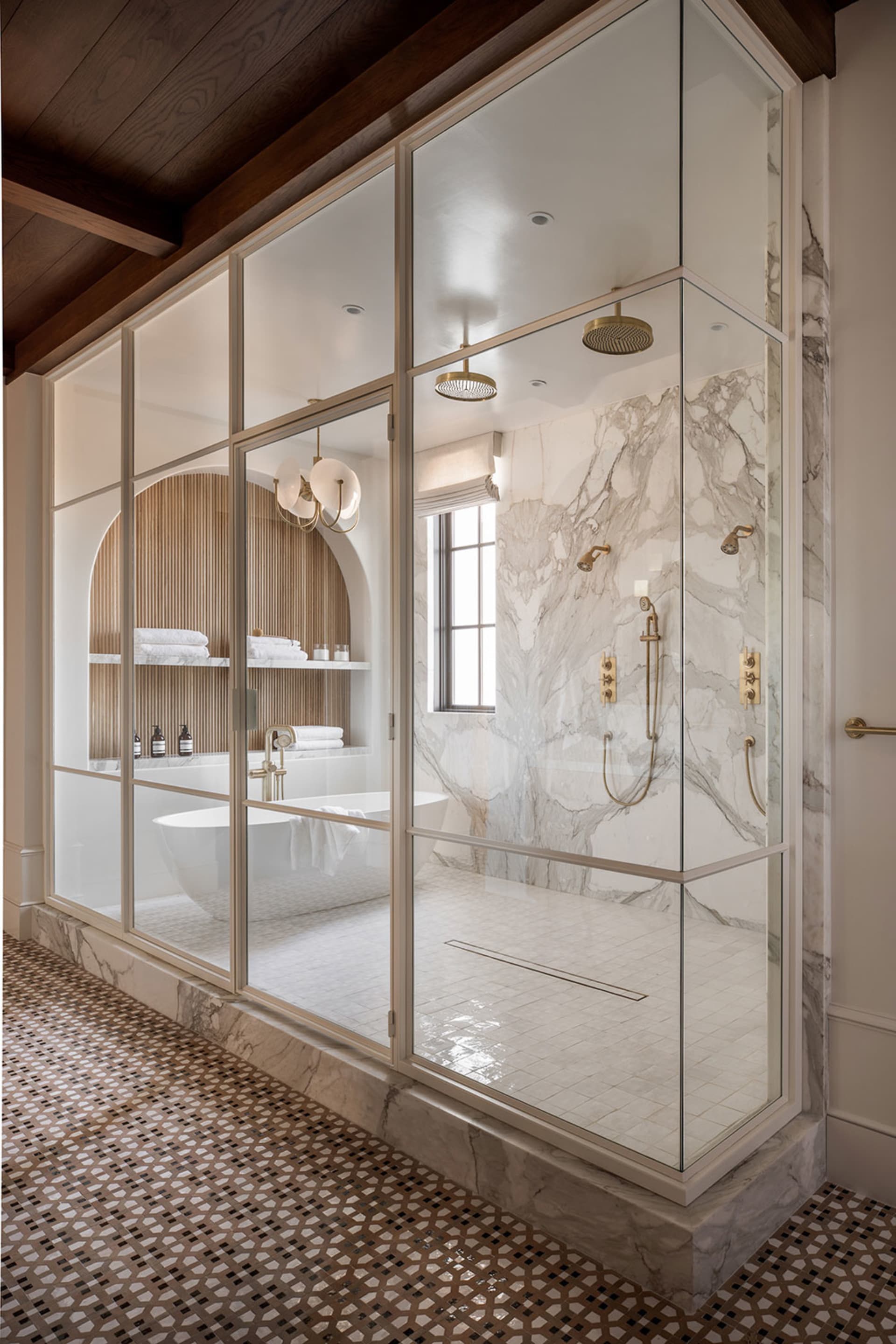 Modern, minimalist bathroom with marble walls and floor, glass shower enclosure, and freestanding bathtub.