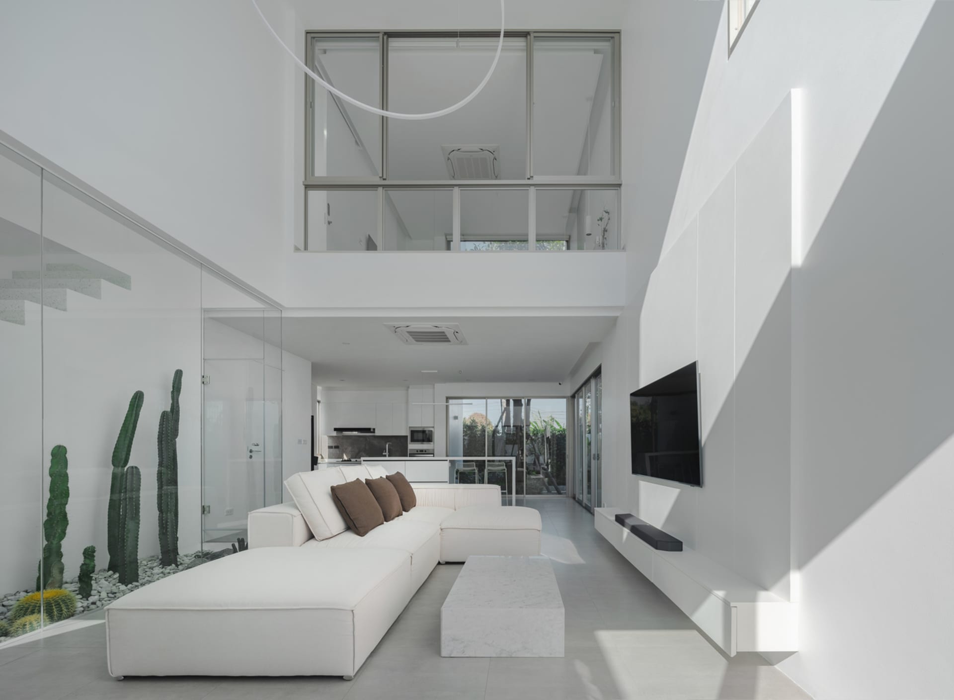 A minimalist living room with white concrete walls, a white sectional sofa, and a concrete coffee table.