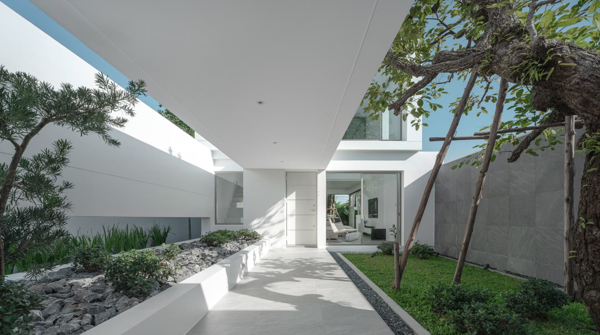 An entrance to a modern minimalist architectural design featuring concrete walls and large glass windows.