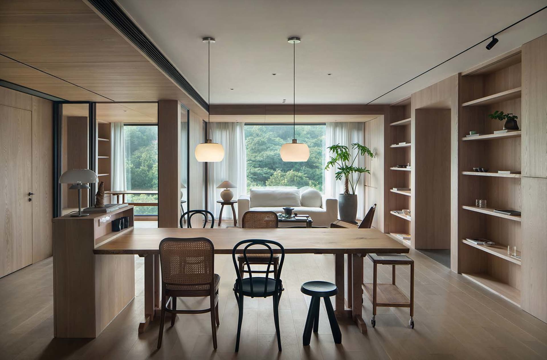 A contemporary minimalist living room featuring a large window with a scenic view, natural wood furniture, and a comfortable 