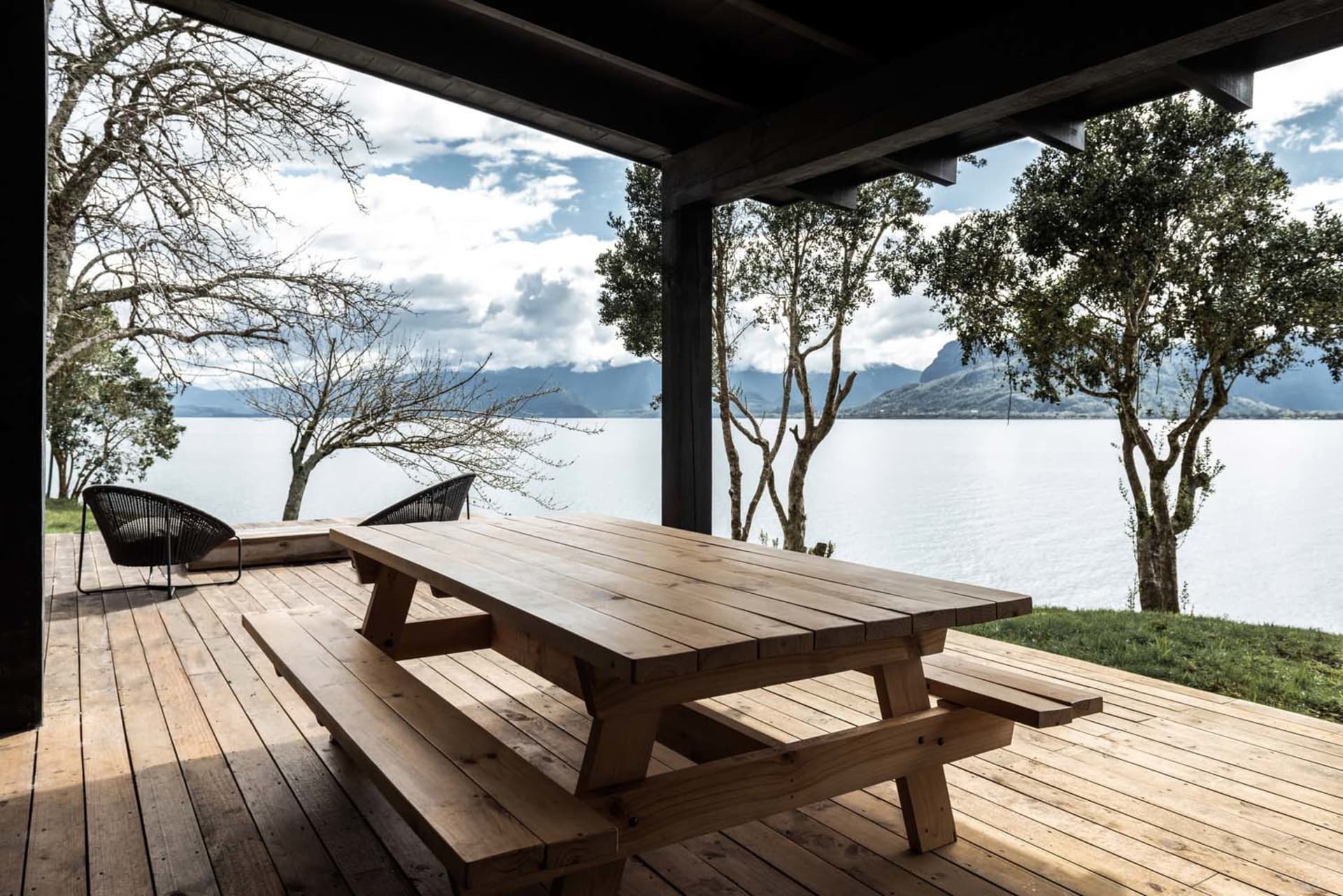 Wooden picnic table on a deck overlooking a lake