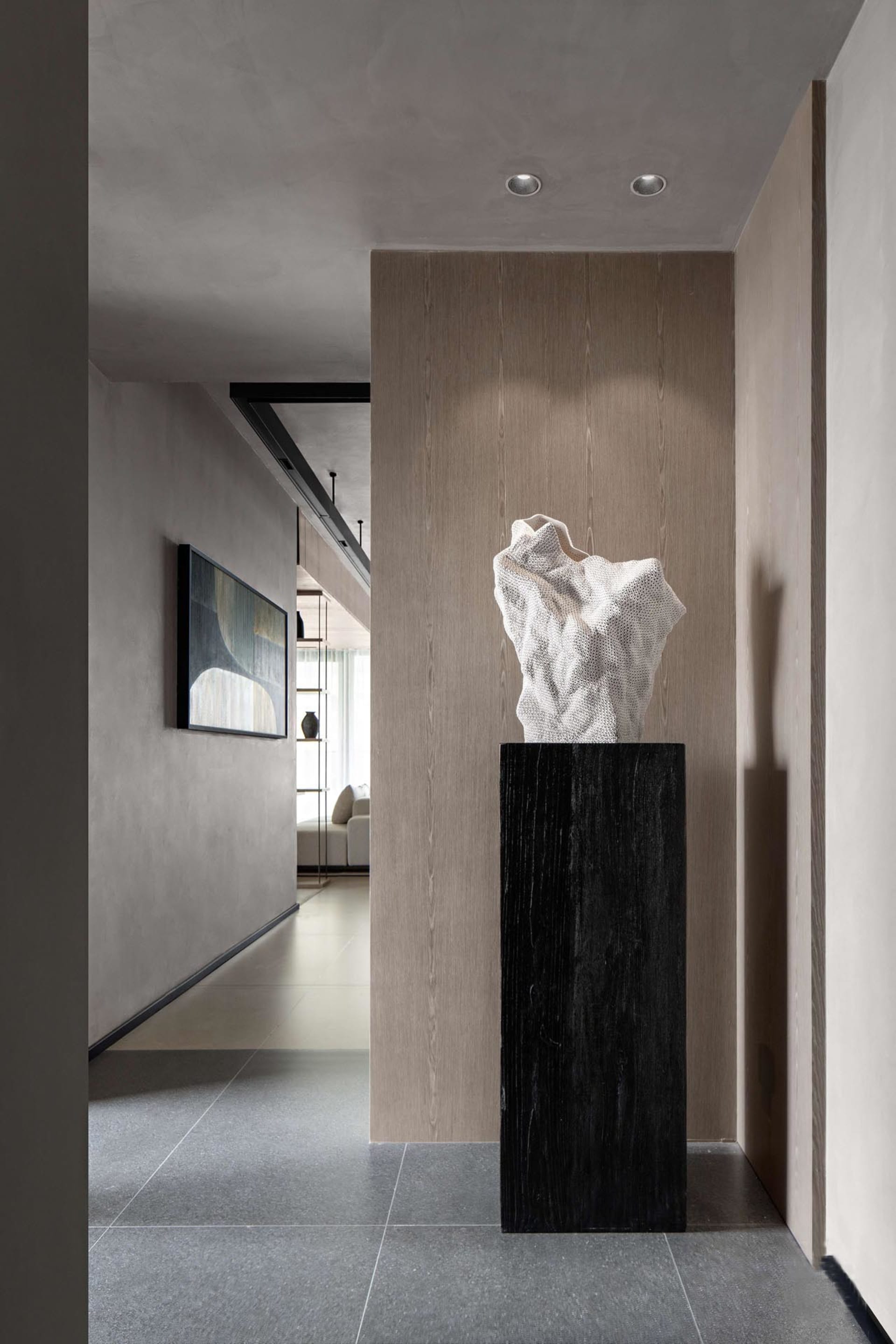 A modern entry hall with a wooden column and a white sculpture on top, featuring a minimalist design aesthetic.