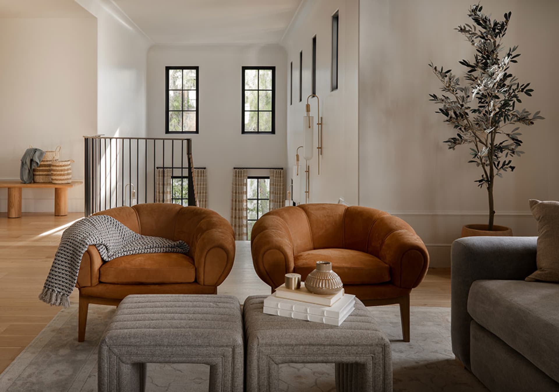 A modern living room featuring comfortable brown upholstered armchairs, a stylish gray sofa, and tasteful decorative accessor