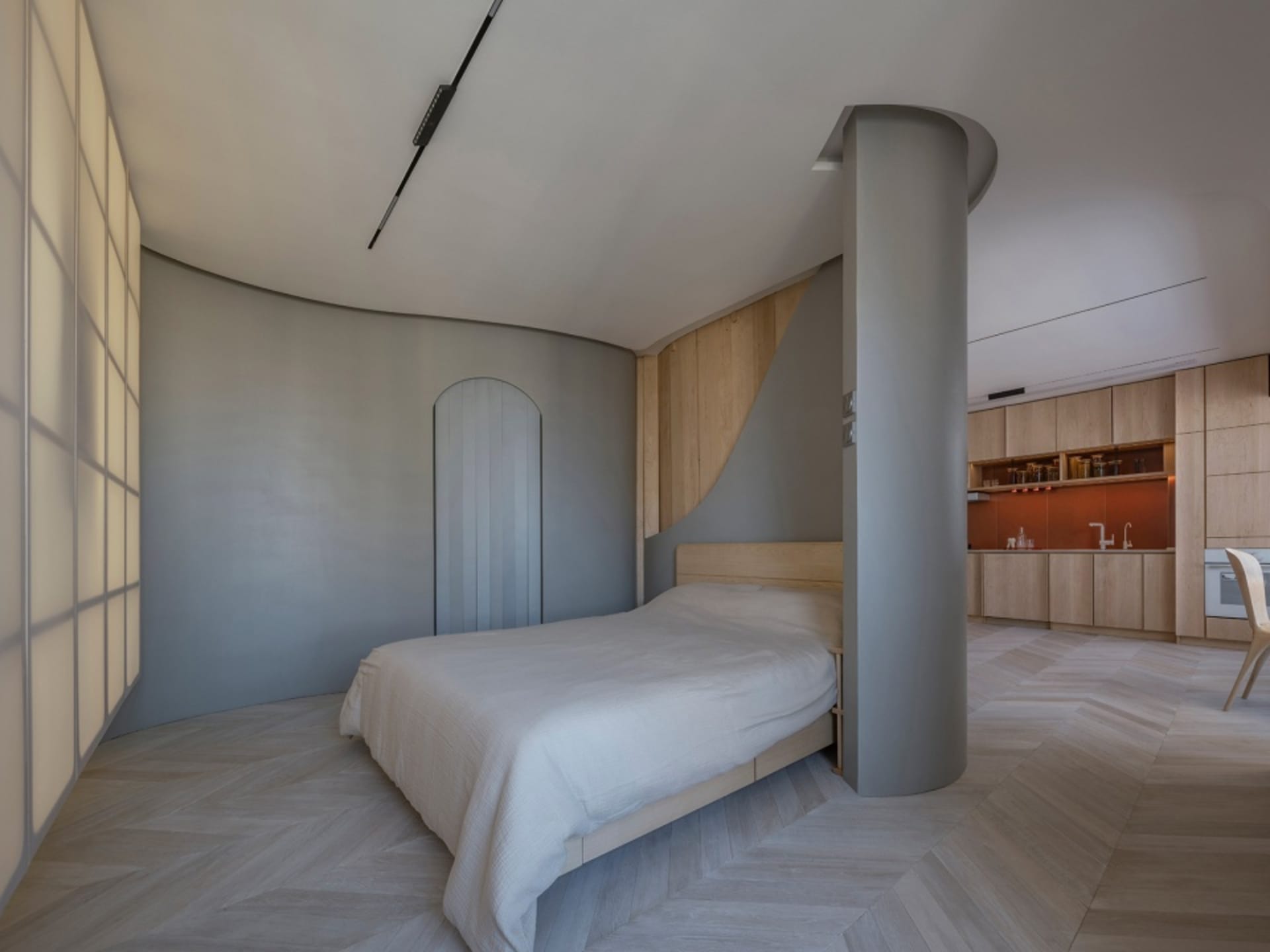 A modern bedroom with light wooden flooring and a bed with a white cover.