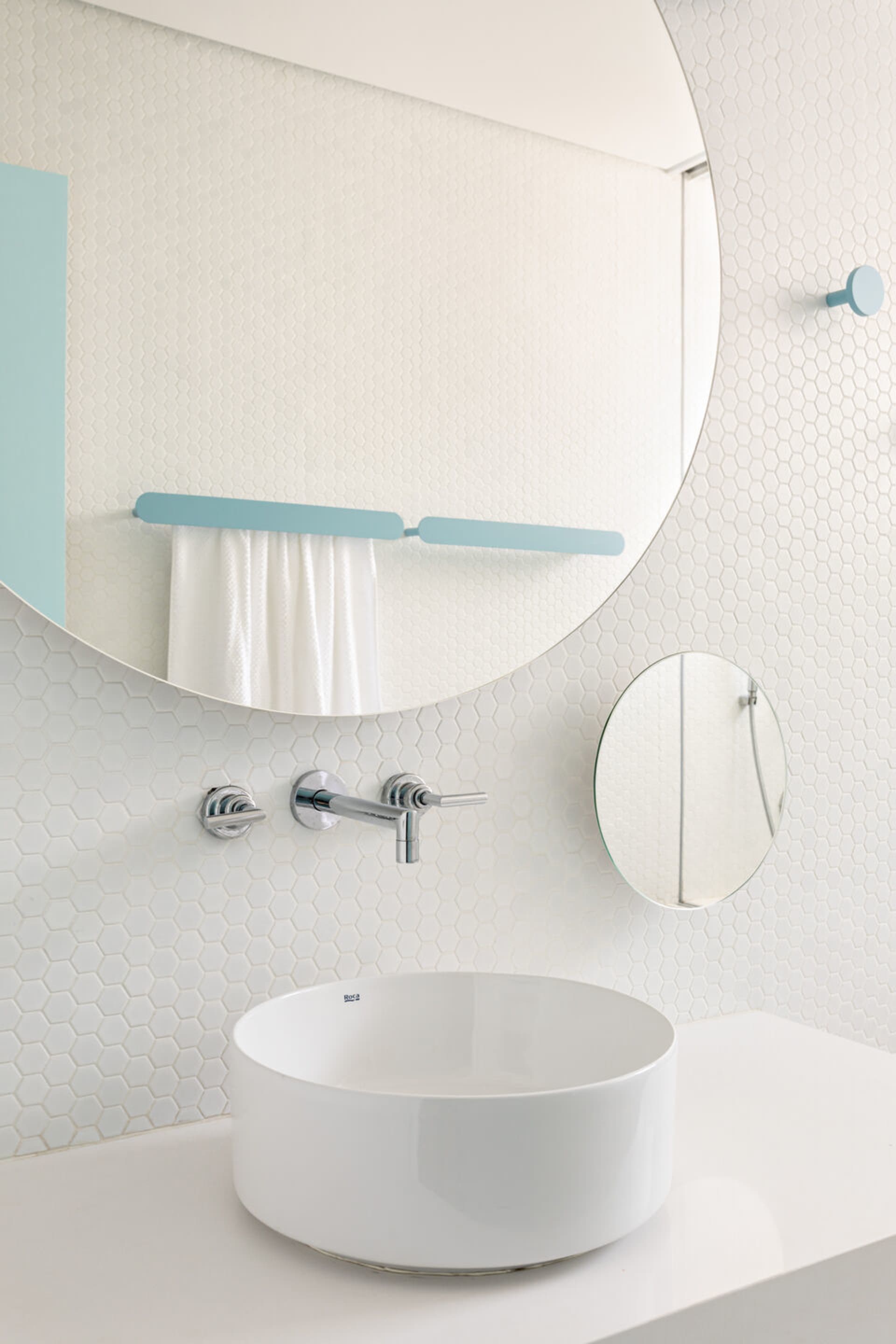 Minimalist bathroom featuring a white ceramic sink with a round shape and a large mirror above it.