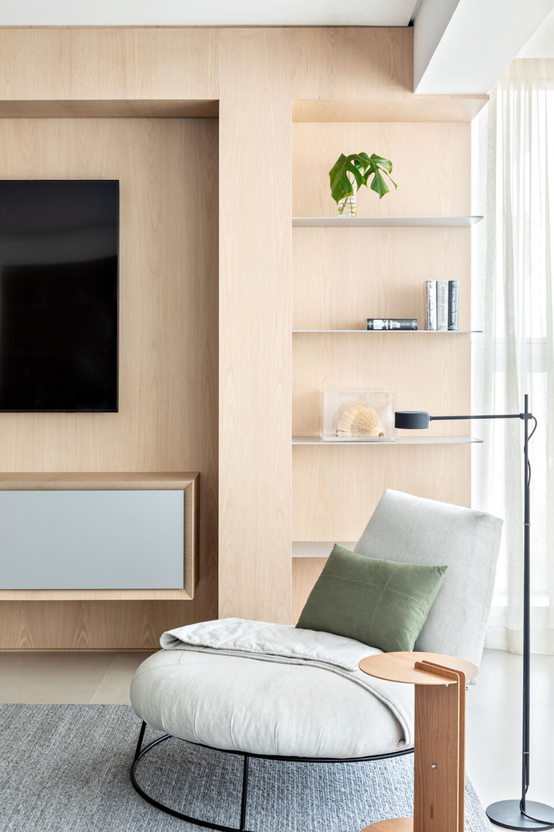 A minimalist living space with wooden walls, a comfortable upholstered chair, and a sleek entertainment unit.