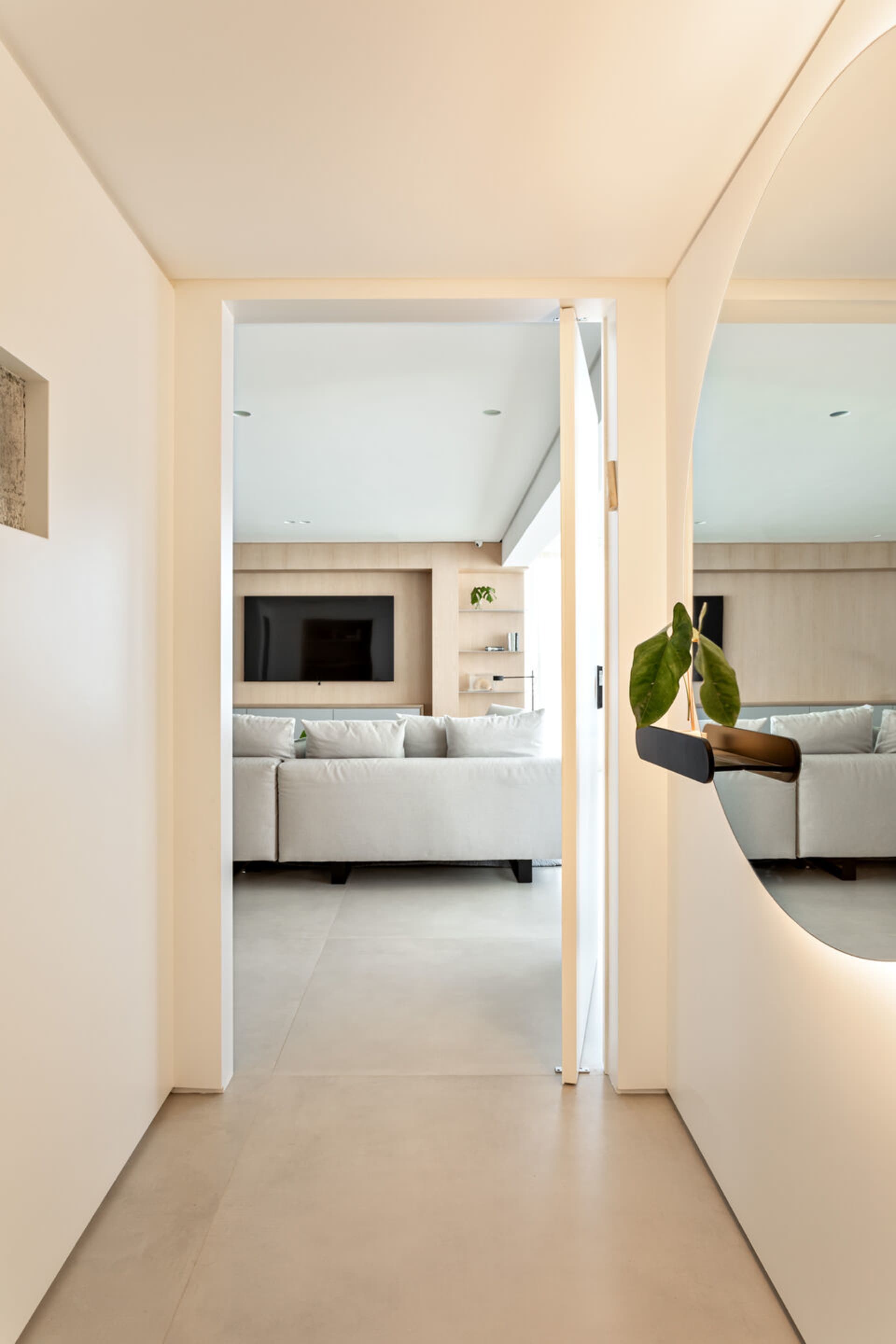 Modern minimalist living room with white furniture and concrete flooring.