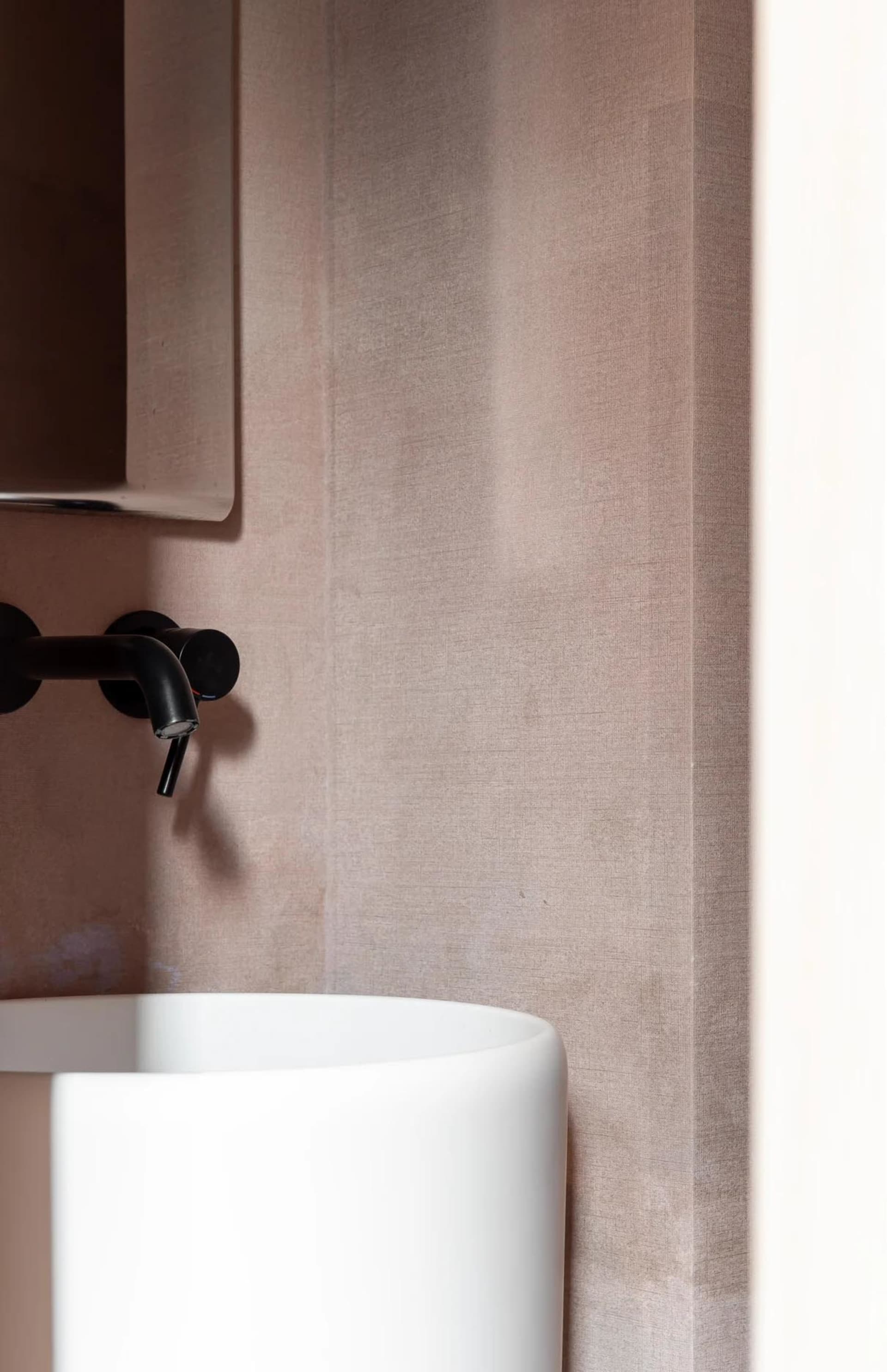 Modern bathroom featuring a minimalist, concrete sink with sleek black faucet.