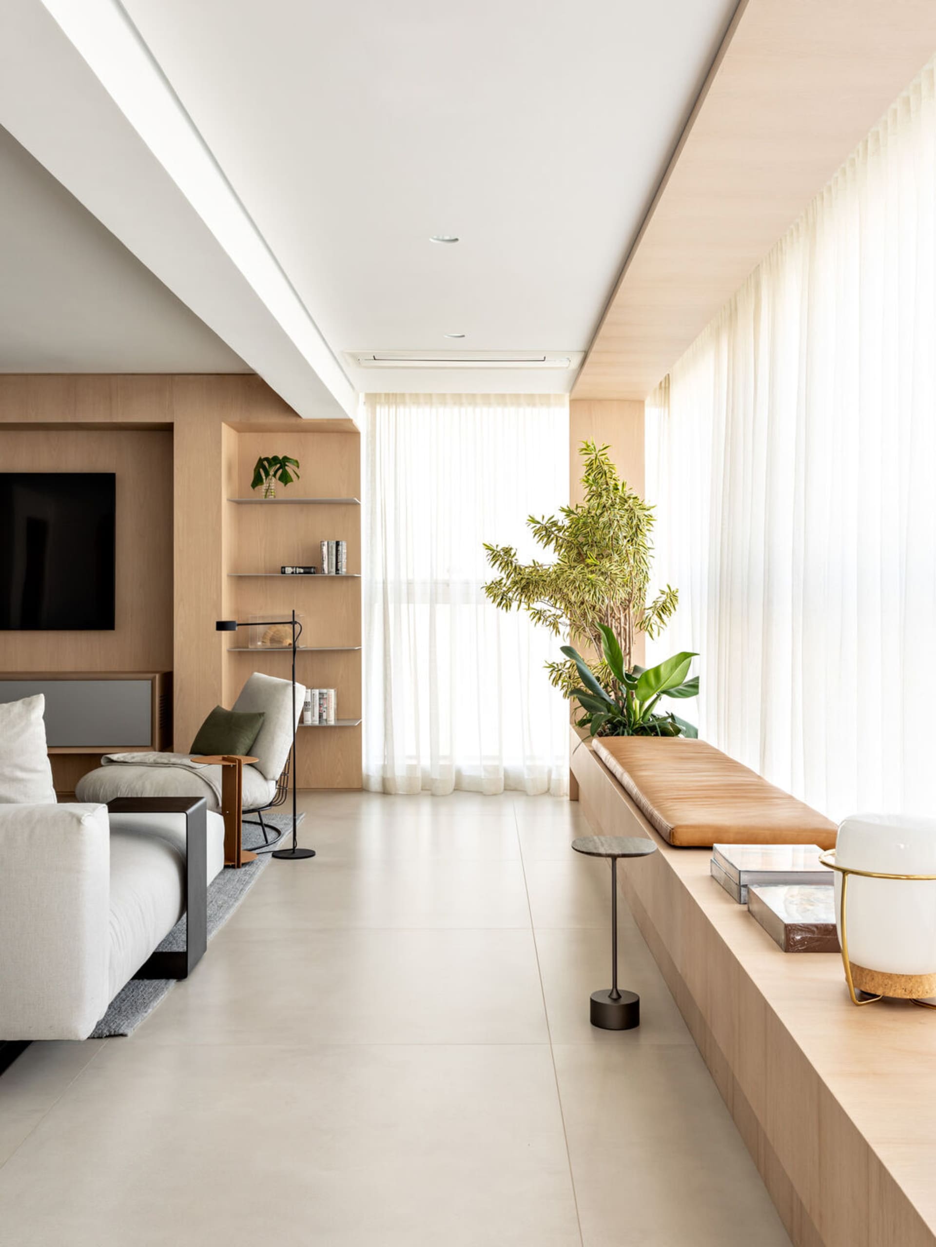 A modern living room with light wood laminate flooring, white walls, and a minimalist design.